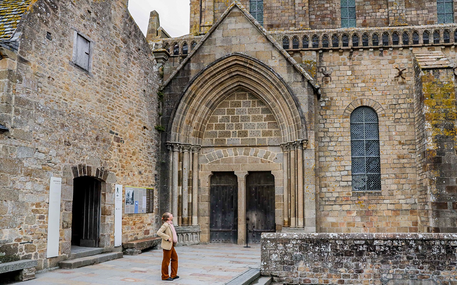 Tourist exploring Mont St. Michel Abbey's historic entrance on a full-day tour from Paris.
