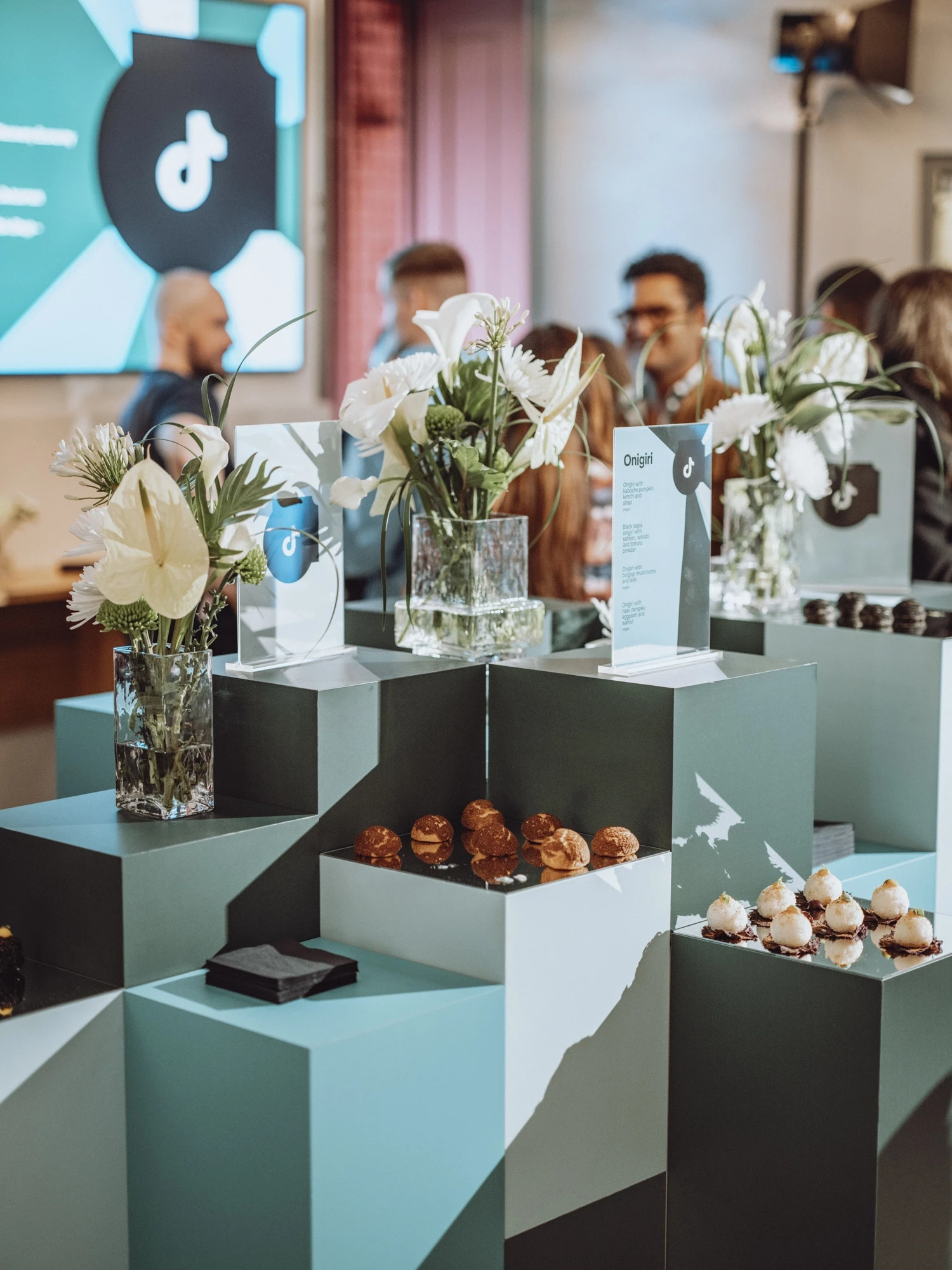 Cubist catering landscape in green tones with canapés, flower vases and menu cards.