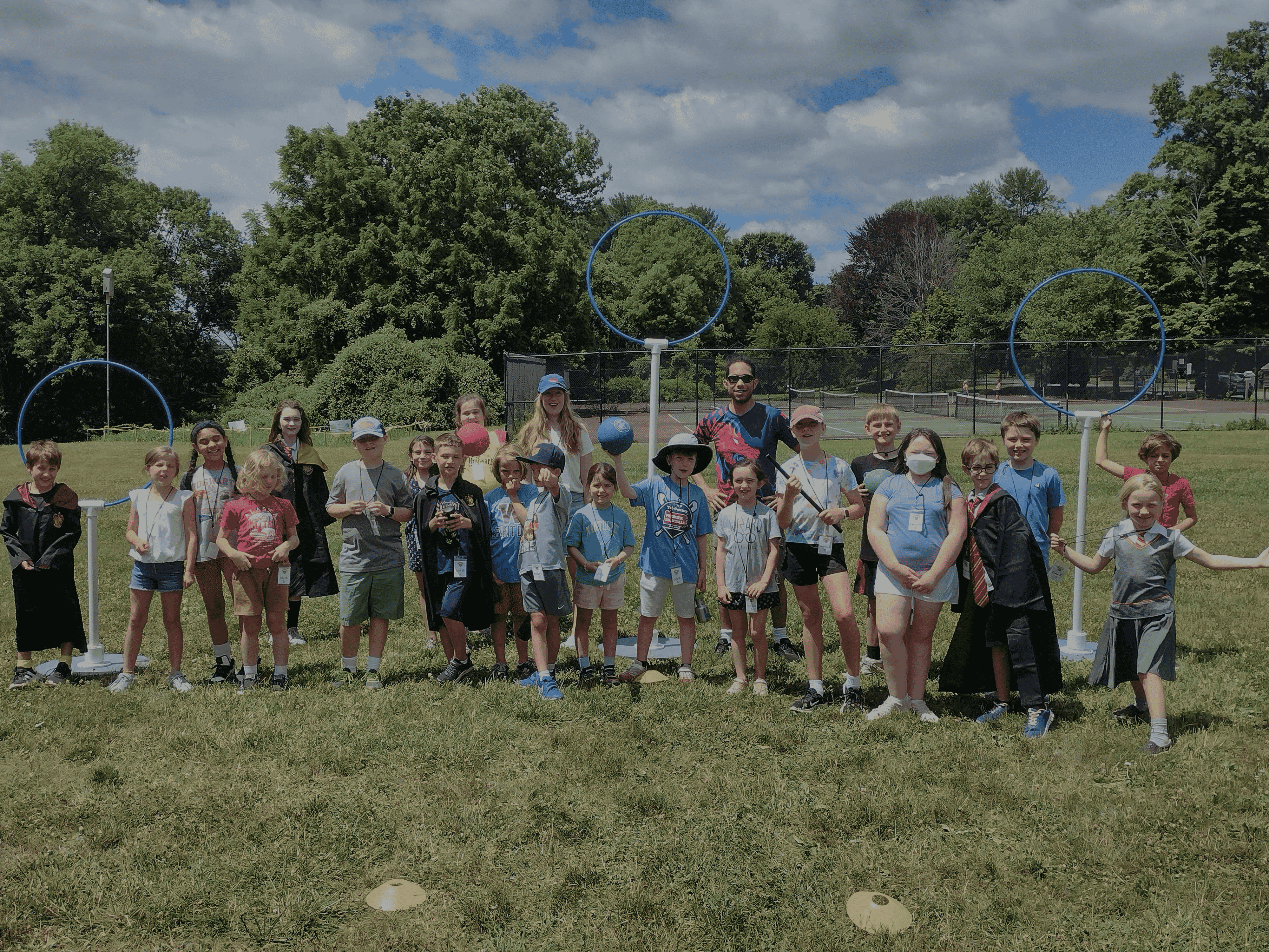 Children in athletic wear and Harry Potter-inspired outfits pose with organizers at a Kidditch event 