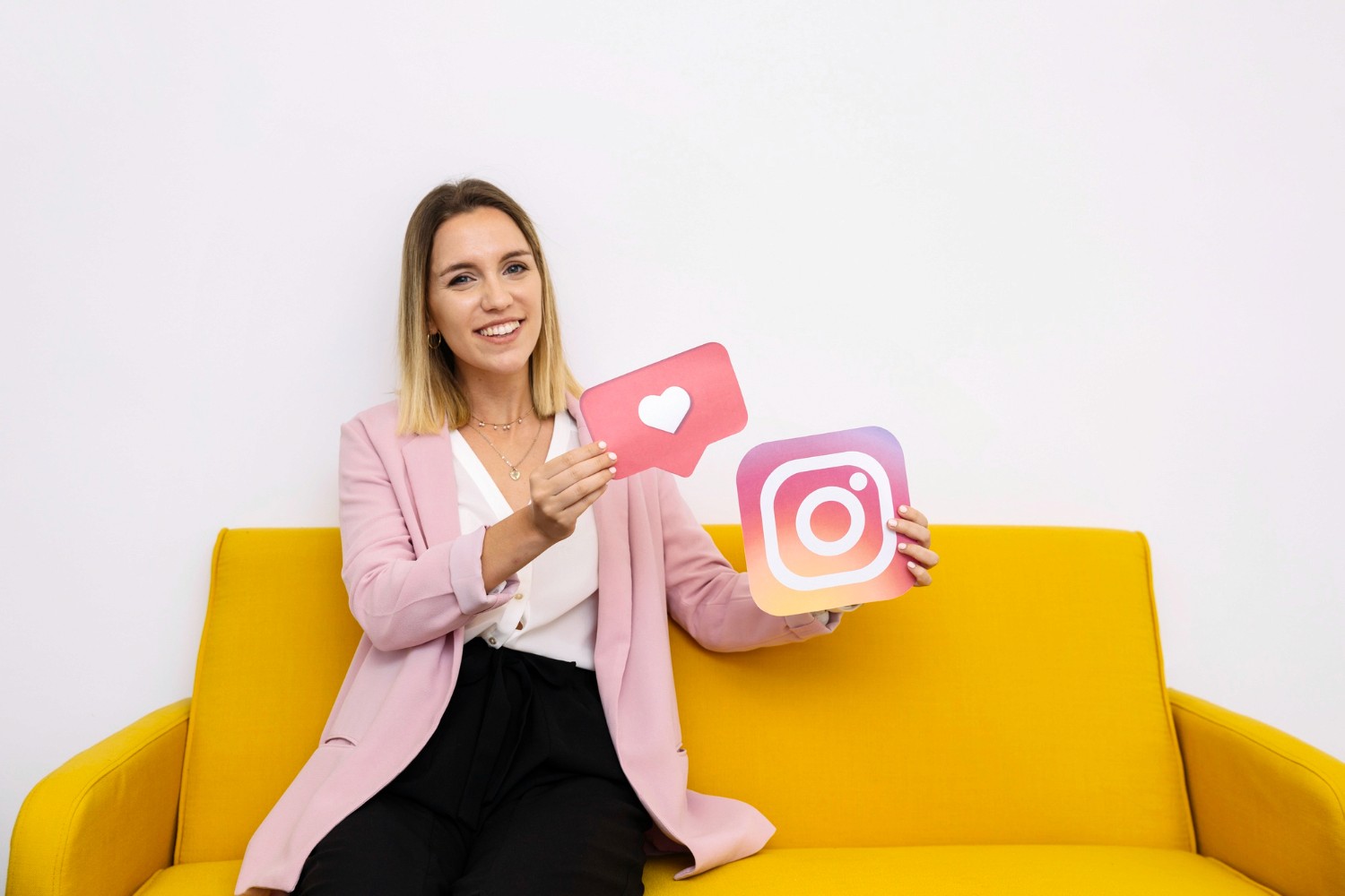  A woman joyfully holds up an Instagram logo alongside a heart symbol, representing social media connection and love.