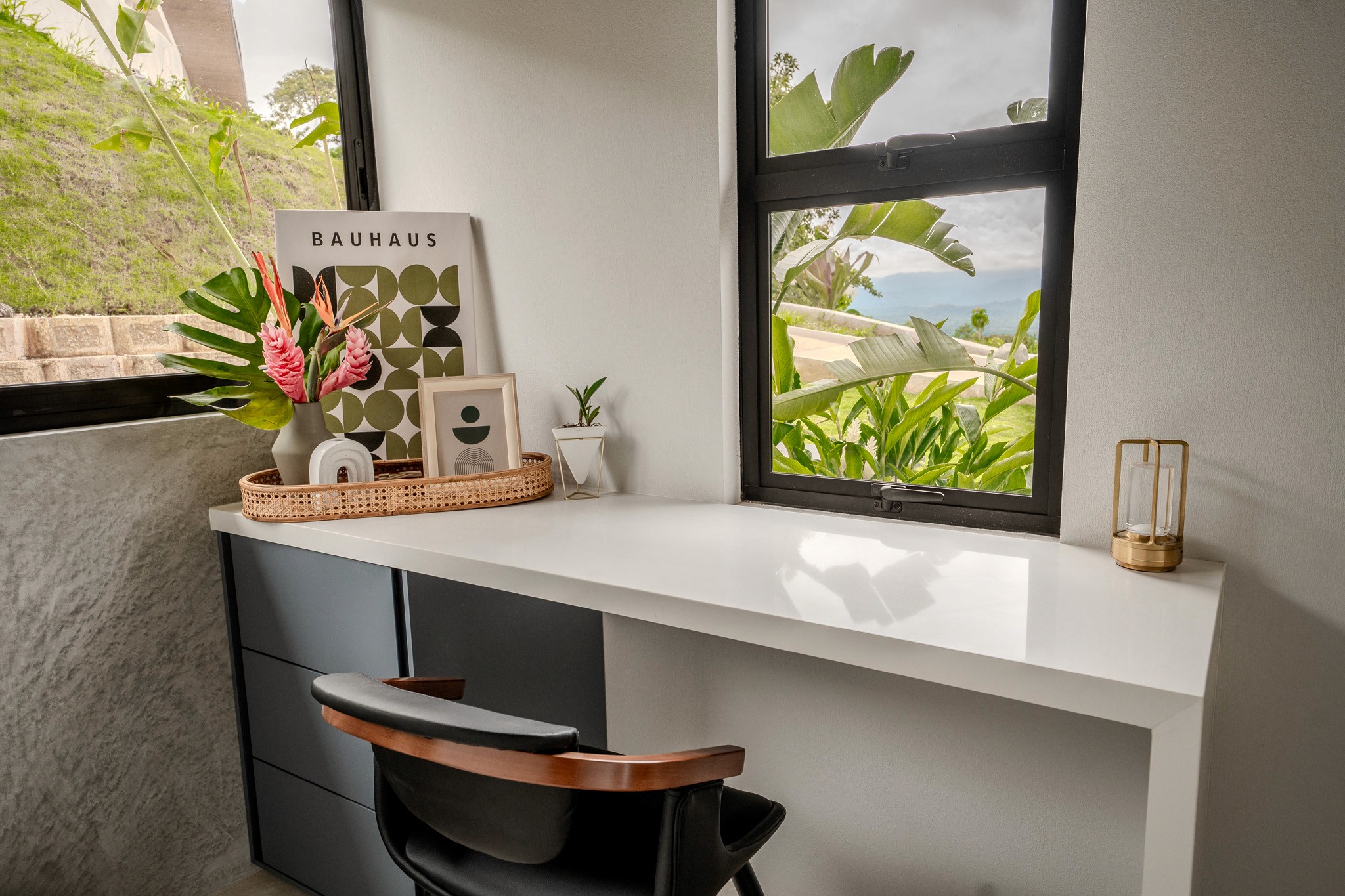 Stylish built-in workspace with a modern desk, chair, and tropical decor next to a window with green views, ideal for remote work in Costa Rica.