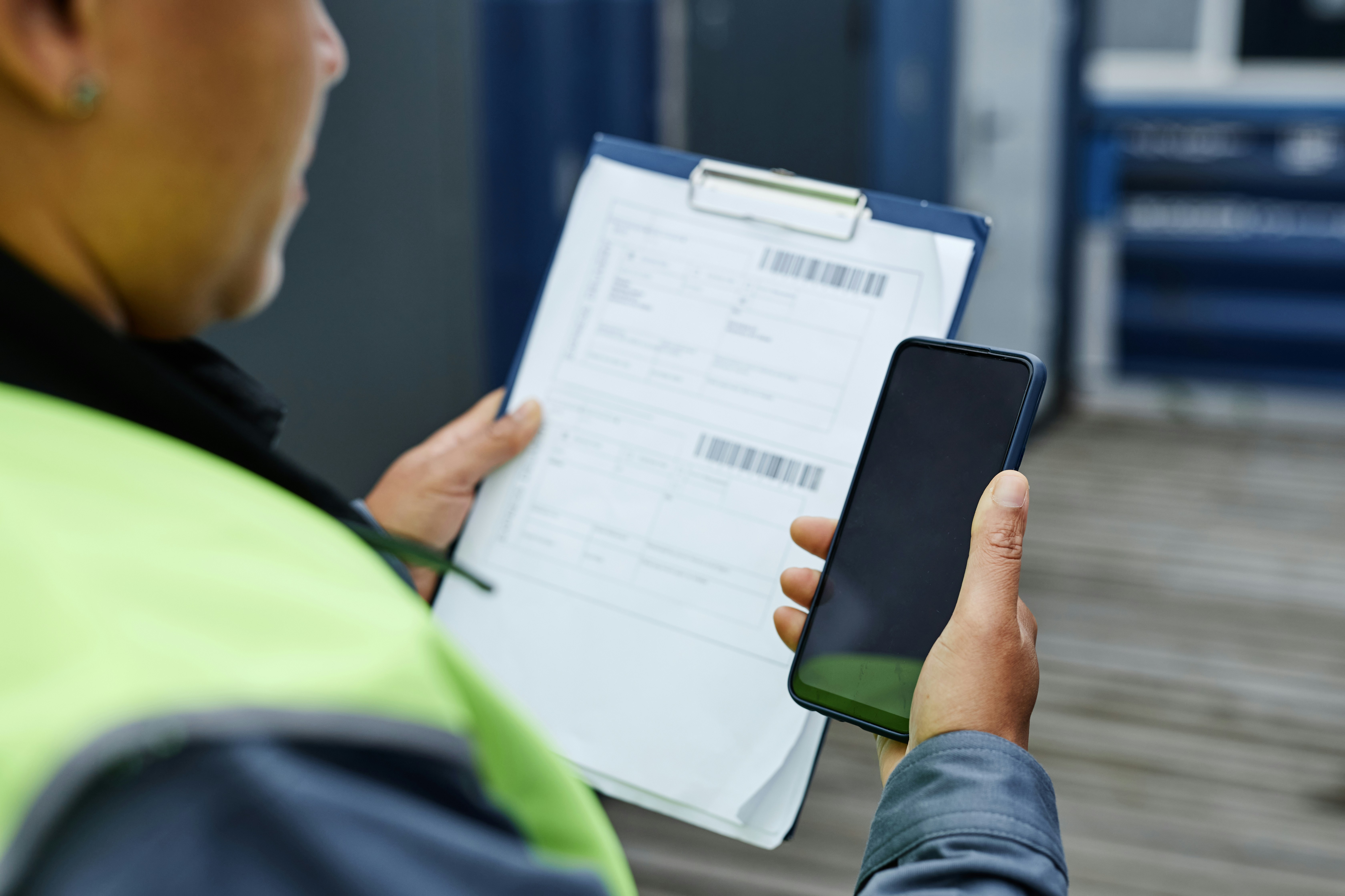 man looks at clipboard and phone during customs clearance