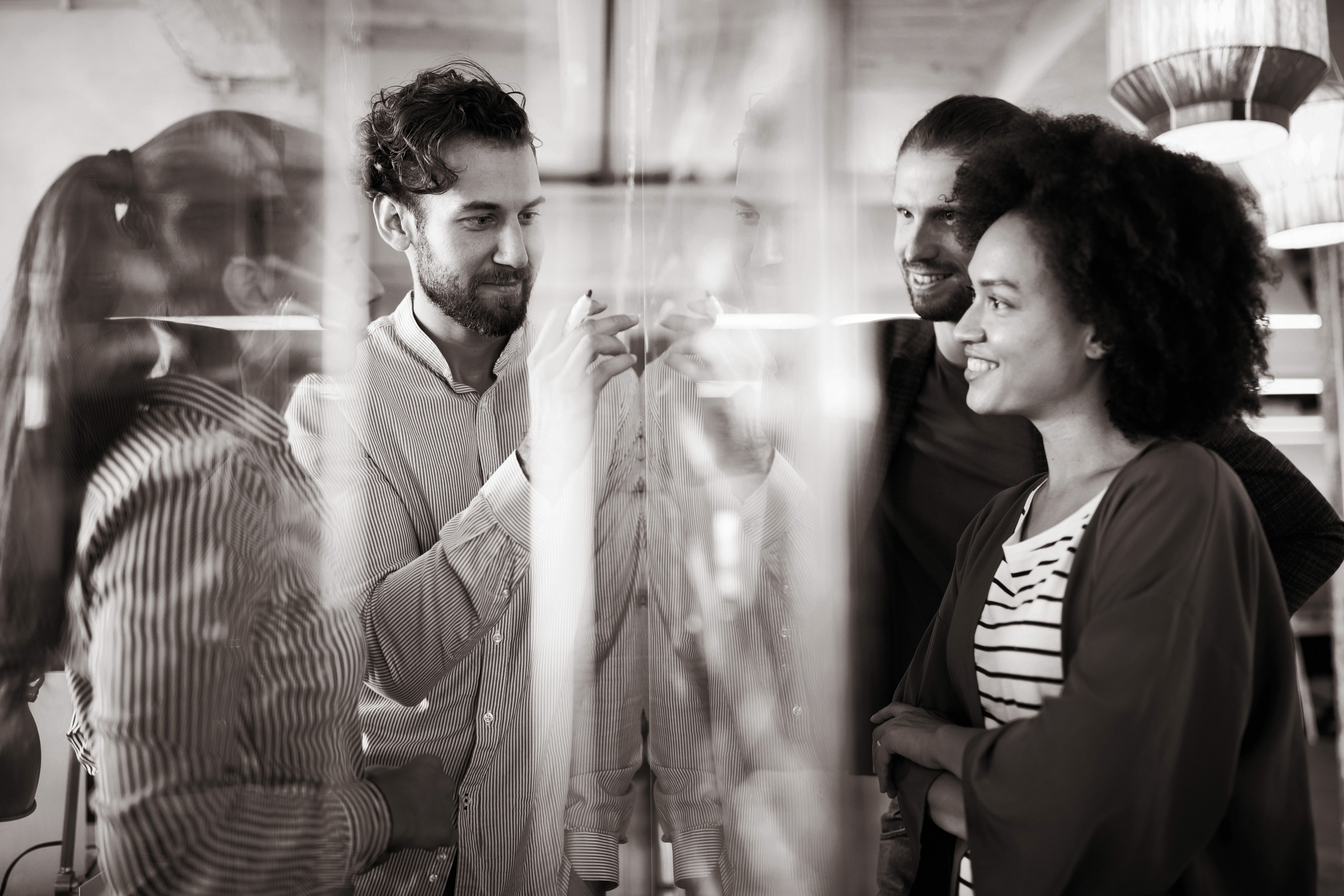 Business meeting and teamwork by business people discussing and pointing at a transparent board in a modern office
