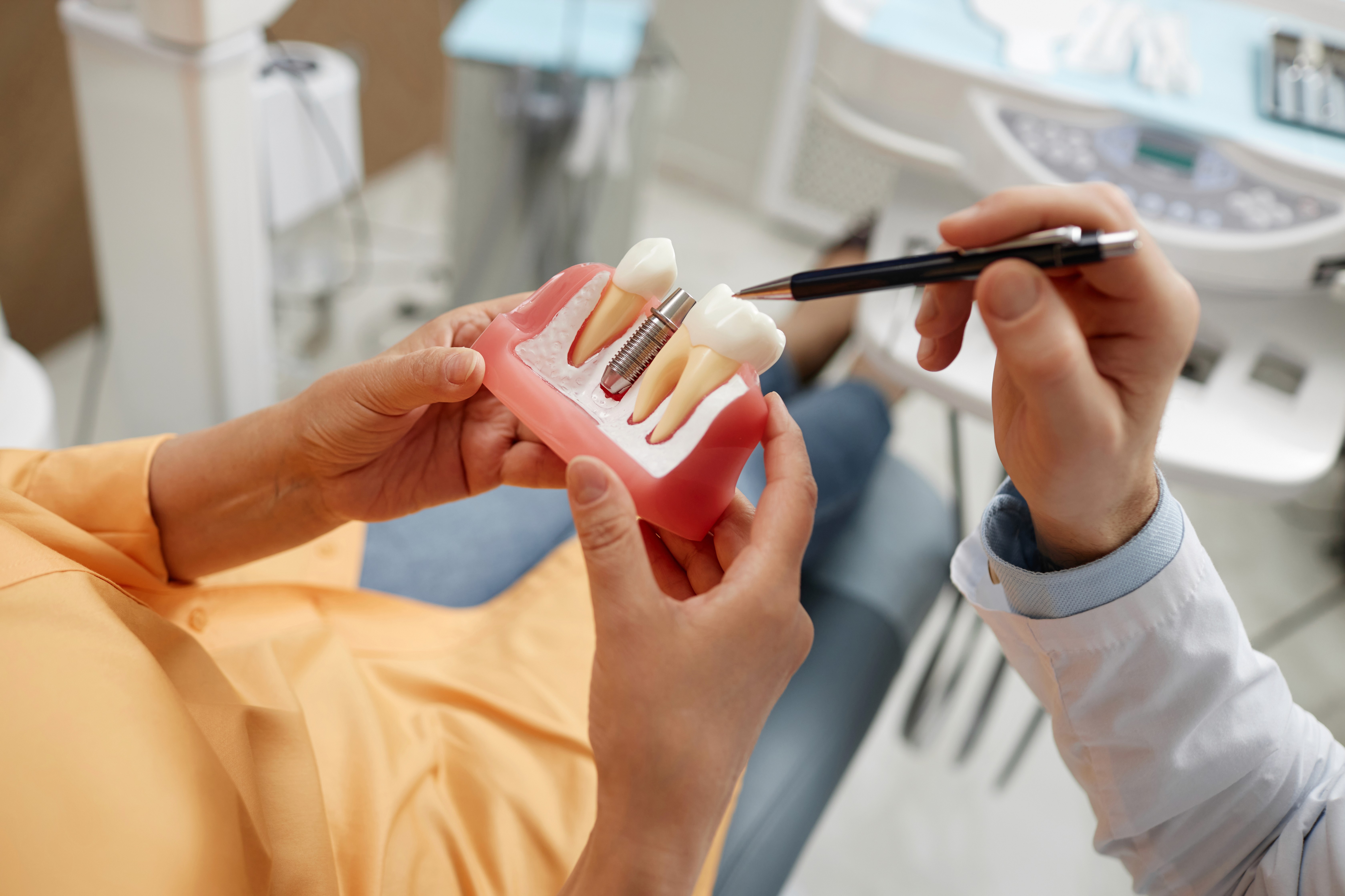 a woman in a dentist's uniform holding a model of a tooth