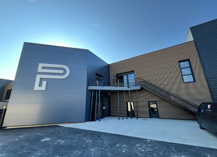 Mur en tôle gris foncé avec signalisation de stationnement blanche peinte au sol.