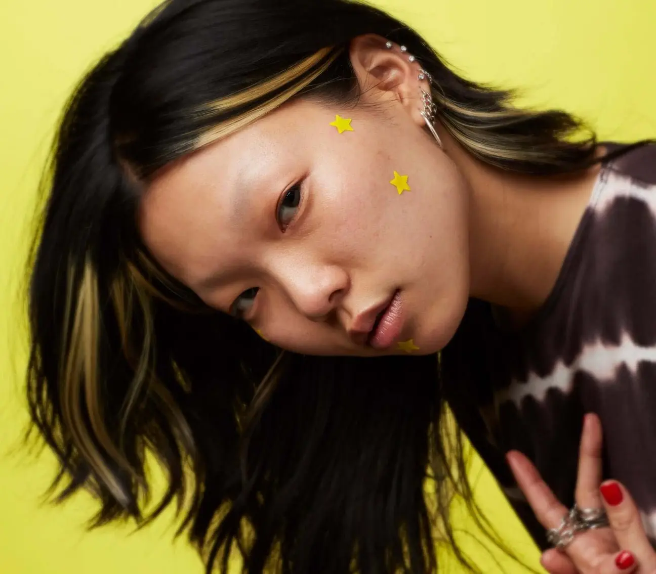 stylised portrait of a woman facing camera wearing a start blemish patch on her face