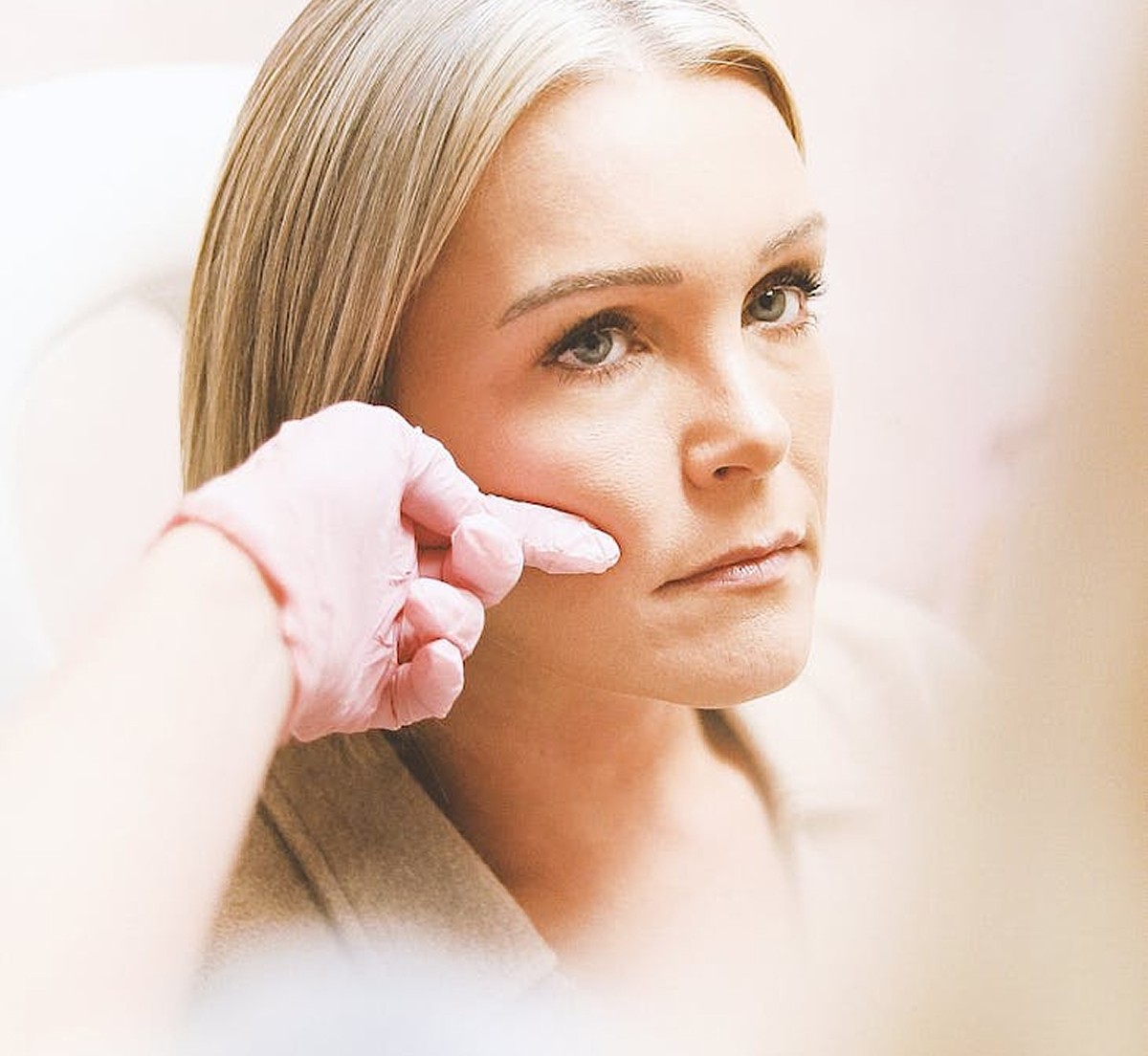 Dermatologist assessing a patient's face during skin consultation.