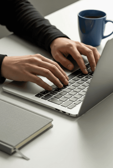 Hands typing on a laptop keyboard, bathed in vibrant teal and pink lighting, creating a dynamic and creative atmosphere.
