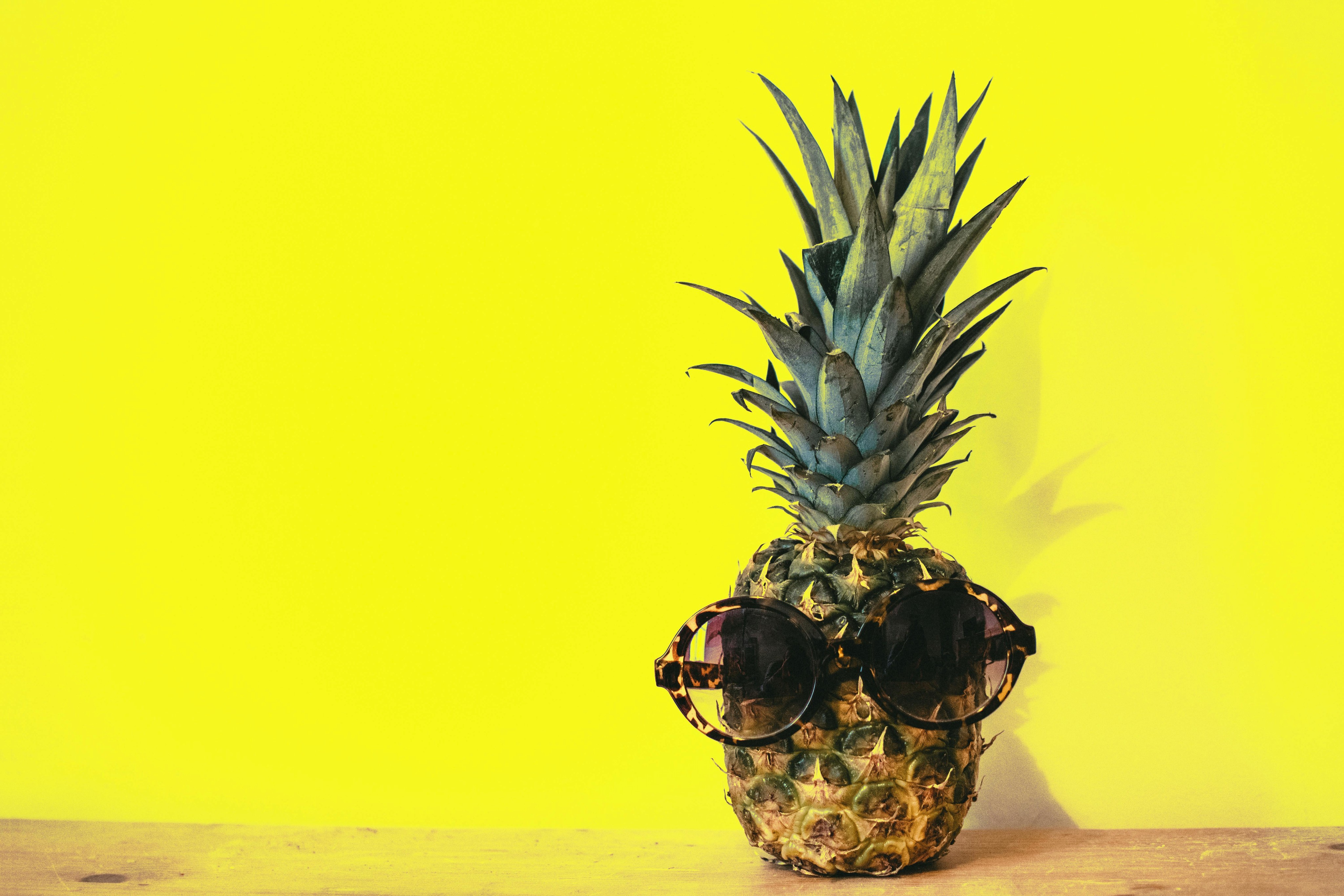 Pineapple with sunglasses, in a yellow background