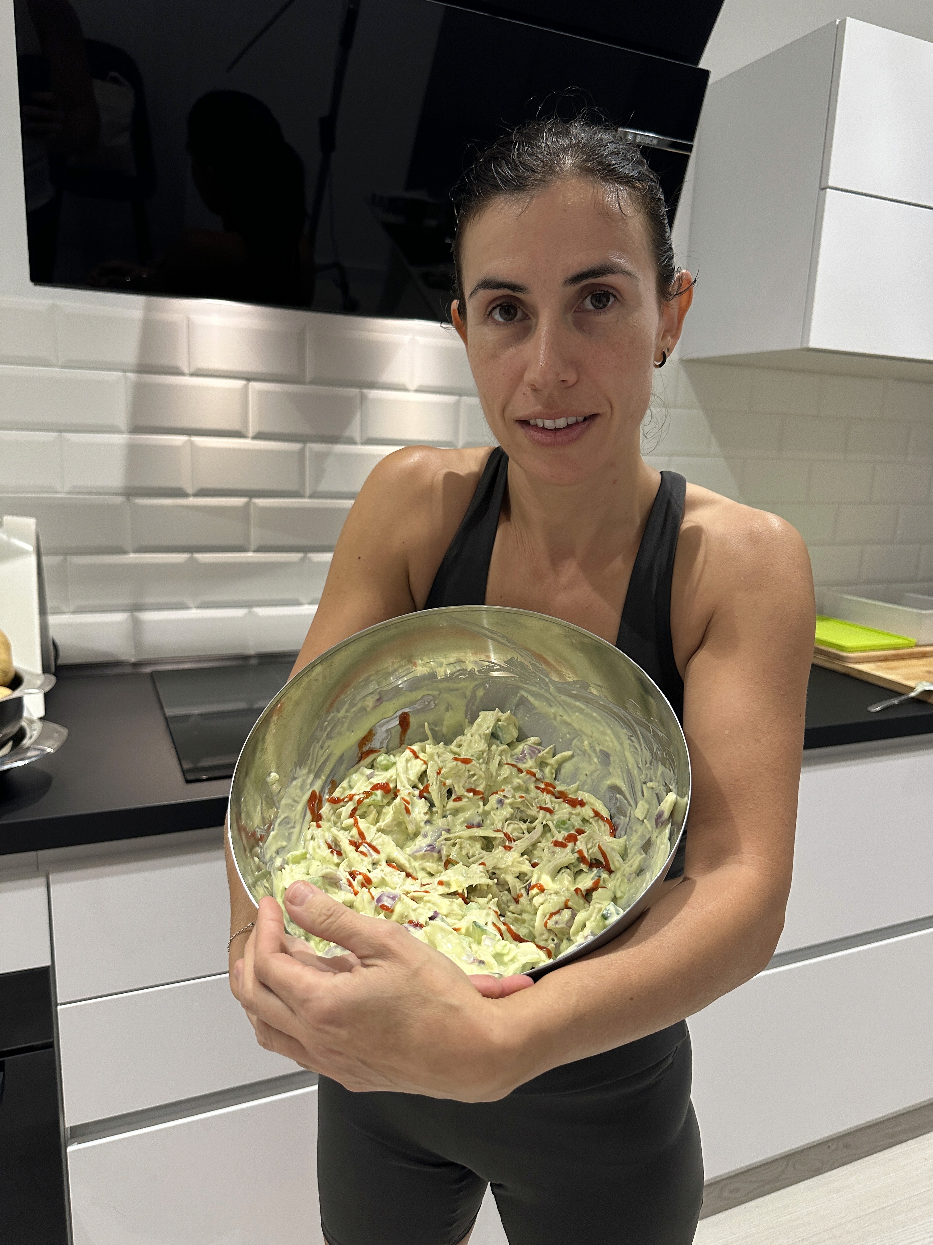 Smiling man sitting at a table with a laptop, phone, and coffee mug, engaged in a video call or online meeting.