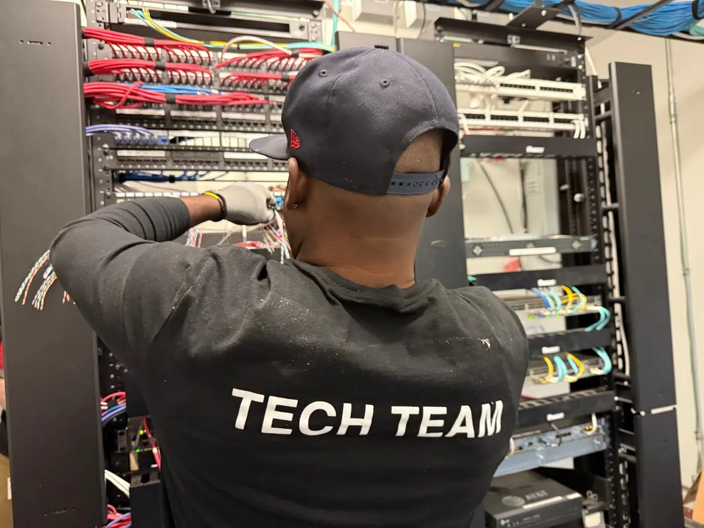 Technician removing network equipment from a server rack, including switches and cabling, during IT decommissioning and hardware removal.