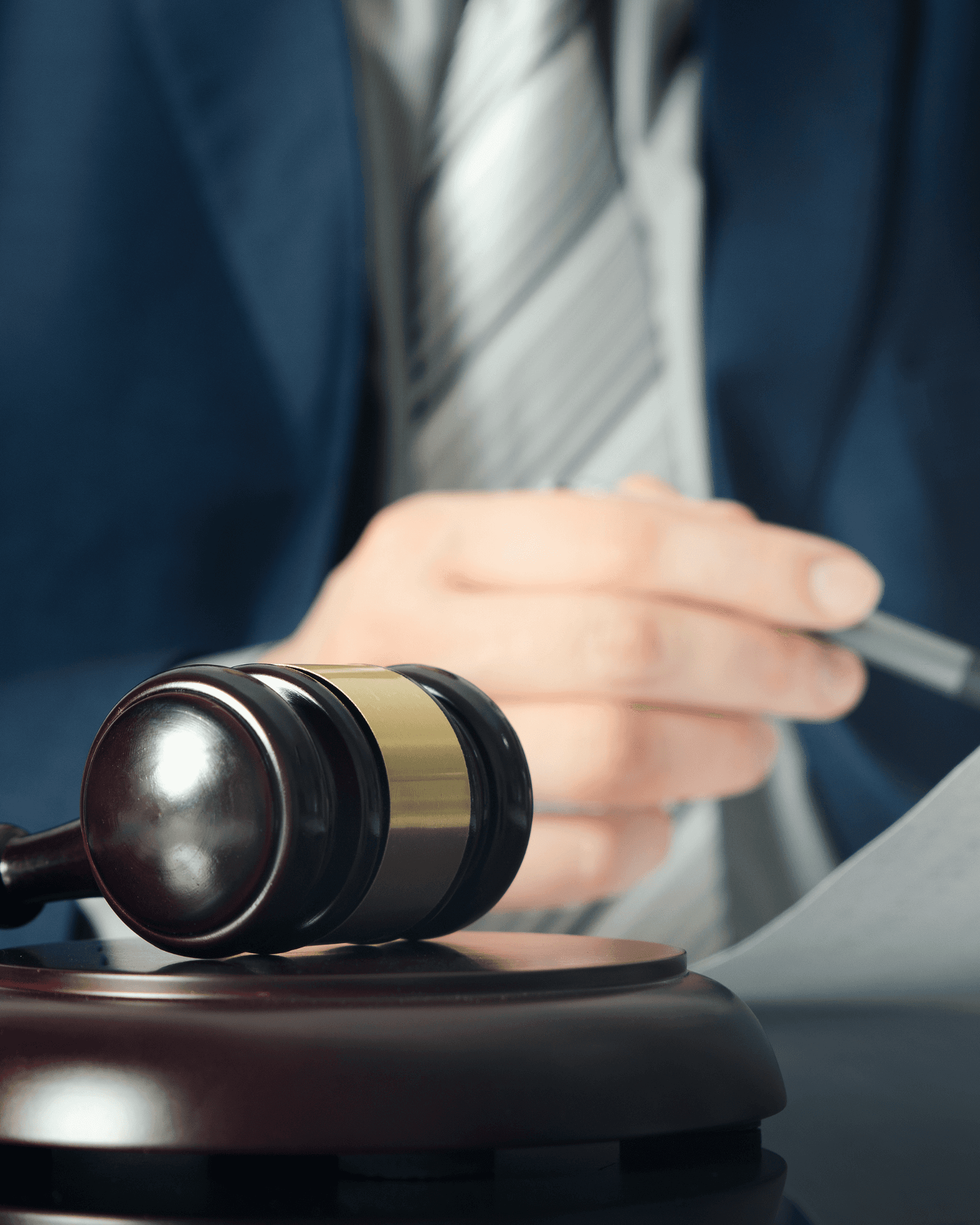 A smiling young man with crossed arms, wearing a plaid shirt and white t-shirt, poses against a dark background.