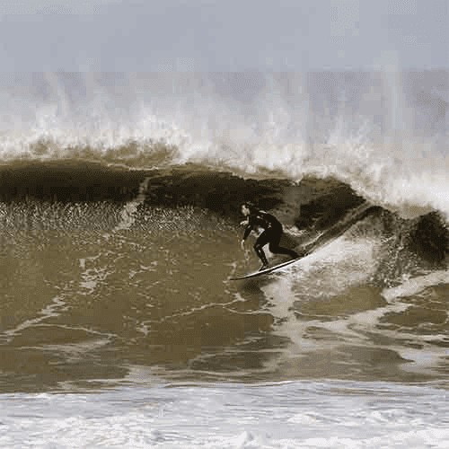 Surfer riding a wave on sunny day – surfboard rental in ericeira