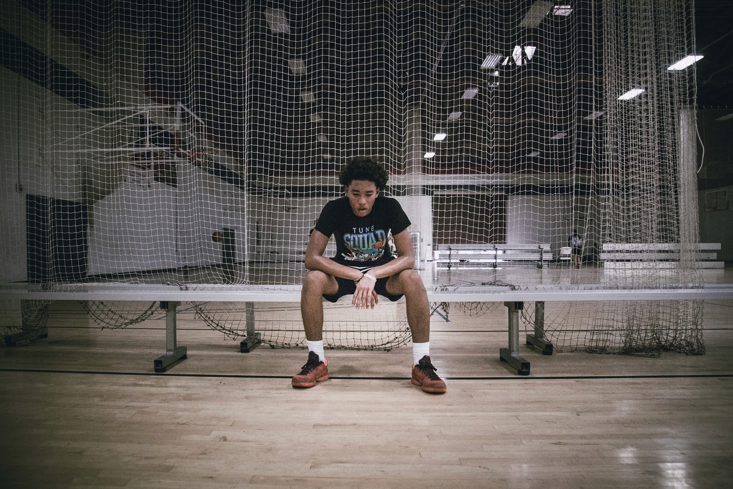 Boy sitting on a bench in a basketball gym