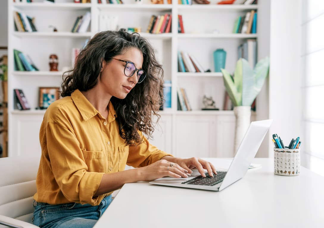Parent of a speech therapy patient using a laptop at home to explore recommended articles and resources, representing empowered and informed caregiving.