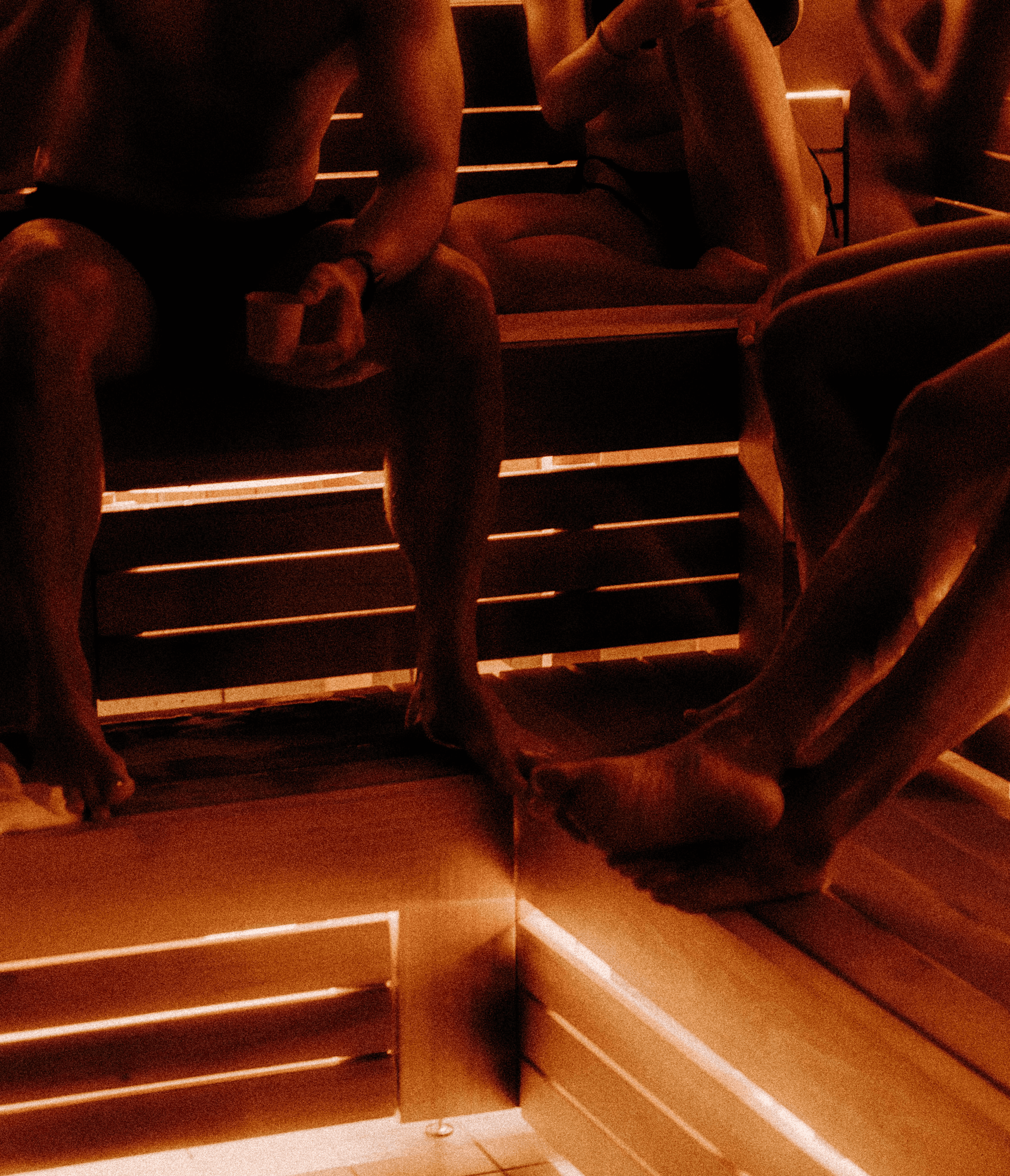 People seated together on warm wooden benches inside a traditional sauna, sharing a quiet communal heat practice