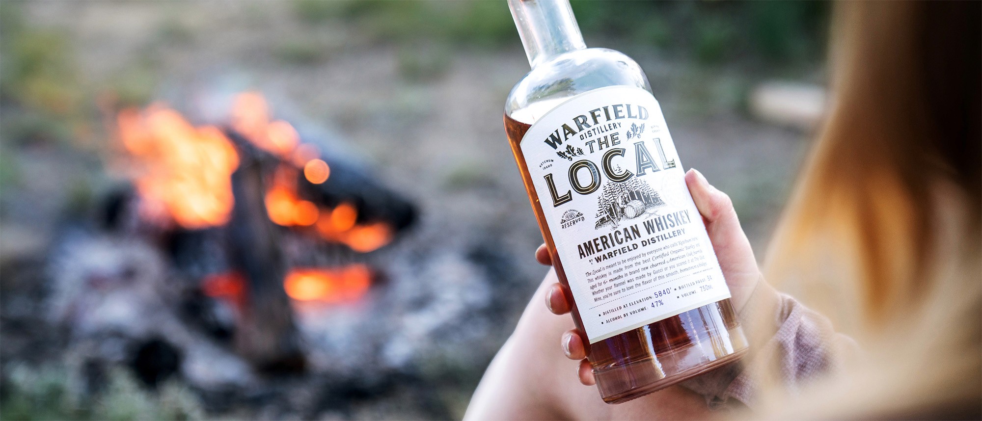 Holding Warfield Whiskey next to campfire