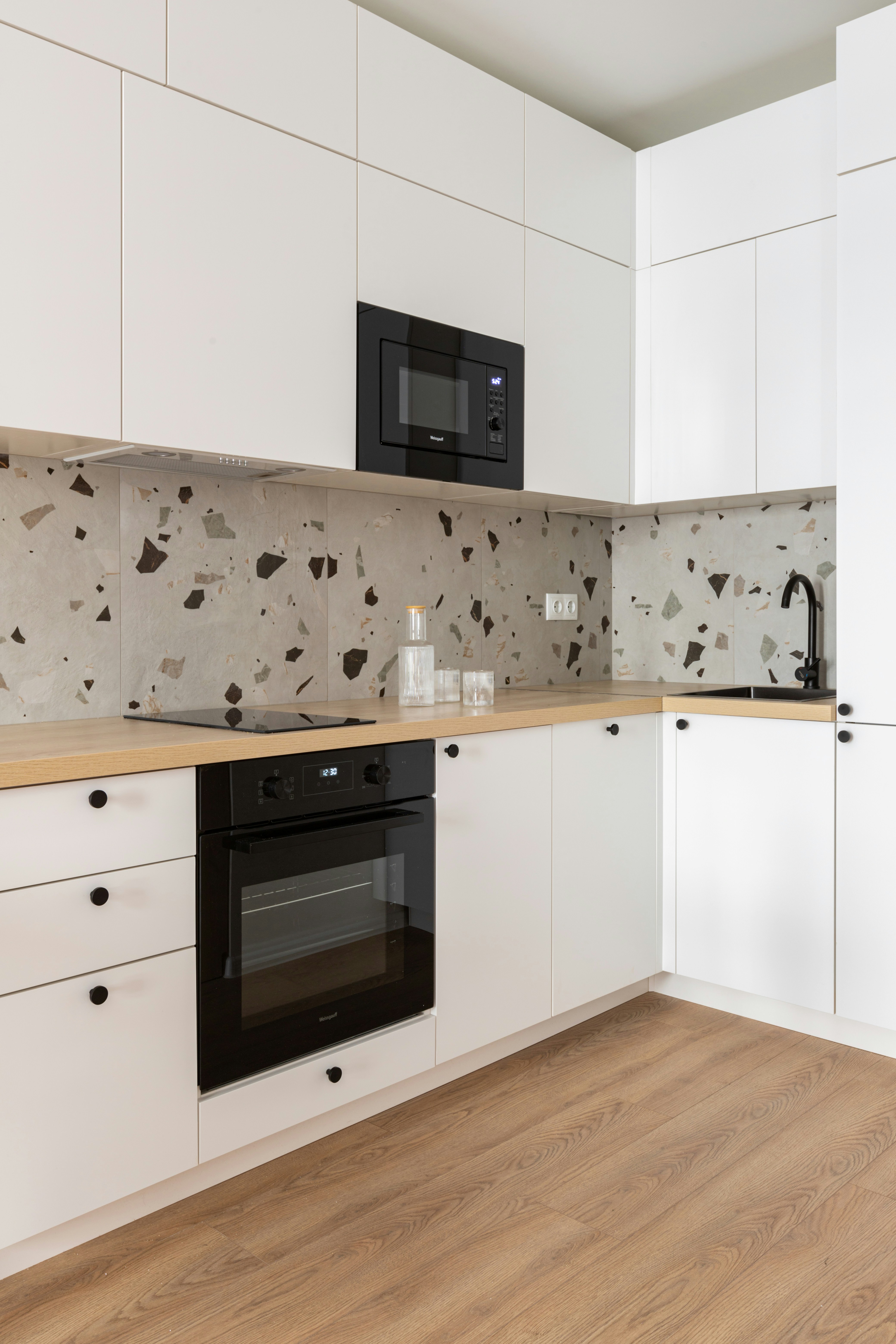 Modern white kitchen with wooden countertops and terrazzo backsplash