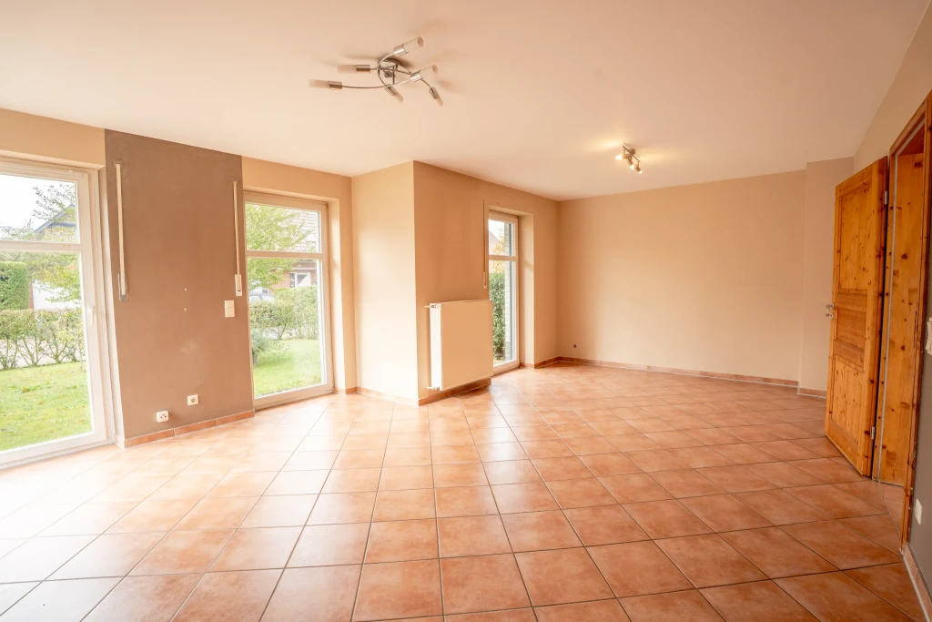 Helles Wohnzimmer mit großen Fenstern und Fliesenboden im Einfamilienhaus in Heek-Nienborg, Westfalen Wohnen.