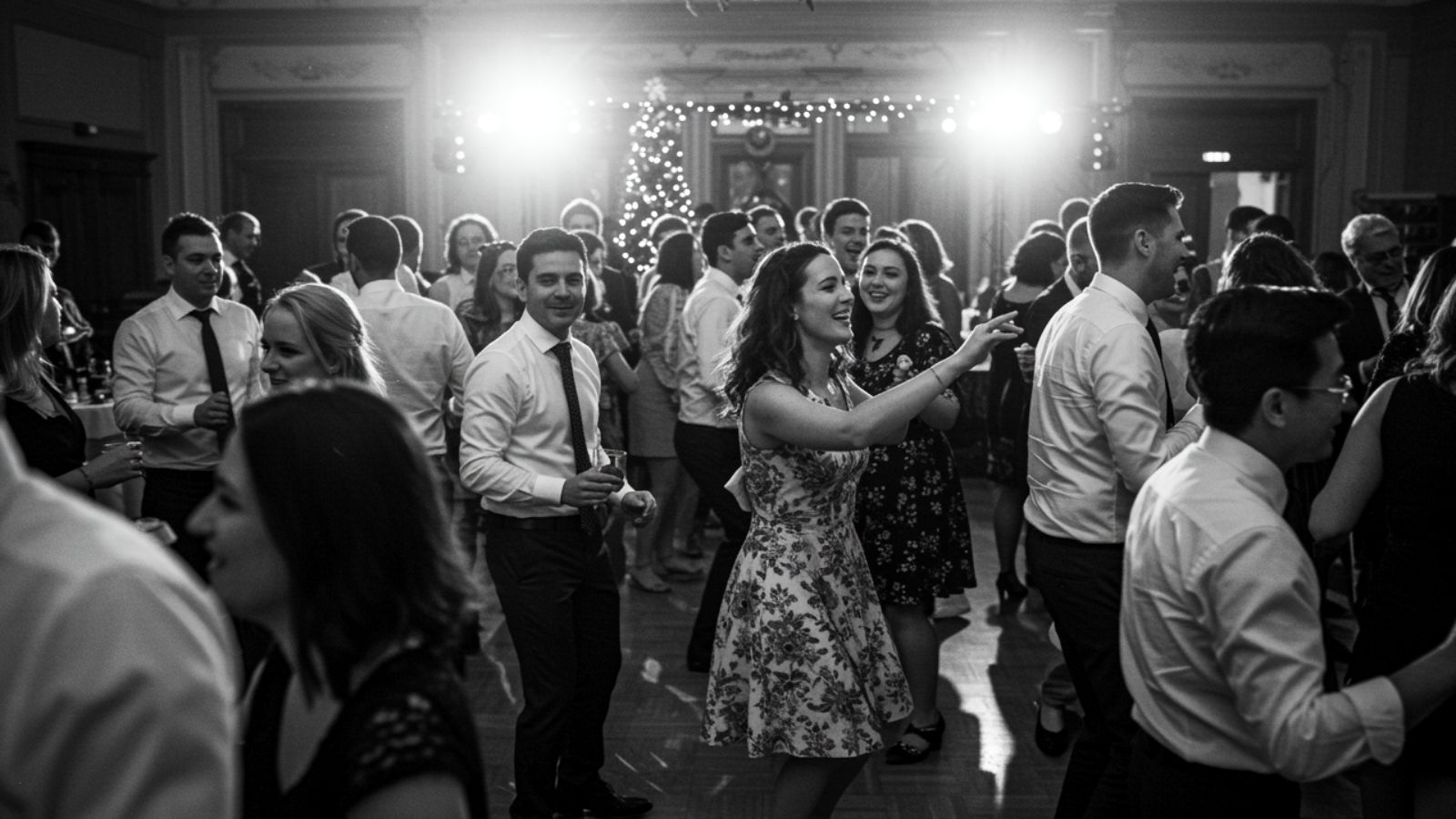 Friends celebrating at a Collingwood Christmas party, raising their hands on the dance floor as snow falls outside the windows and holiday lights shimmer inside.