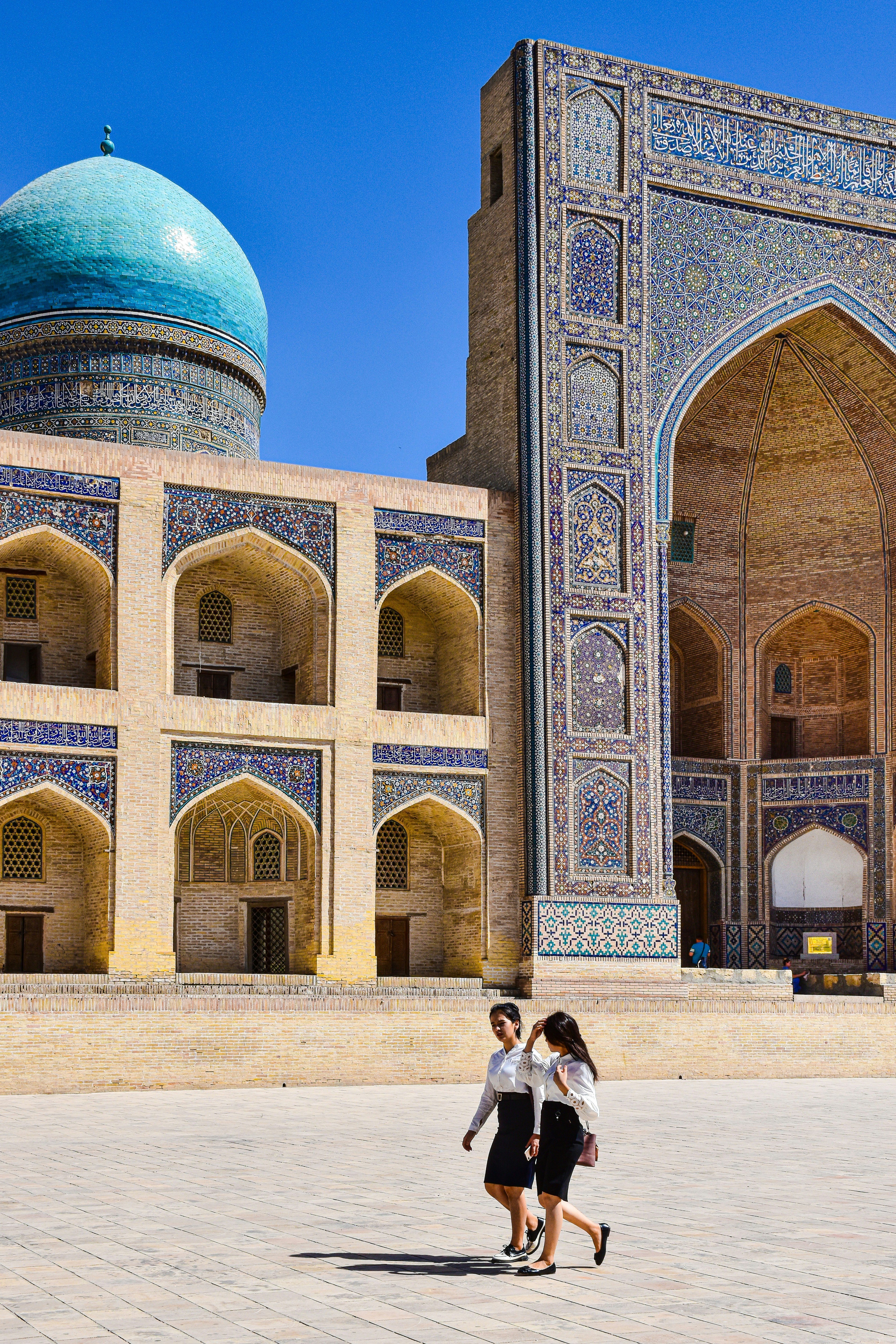 a man and woman posing in front of a large building