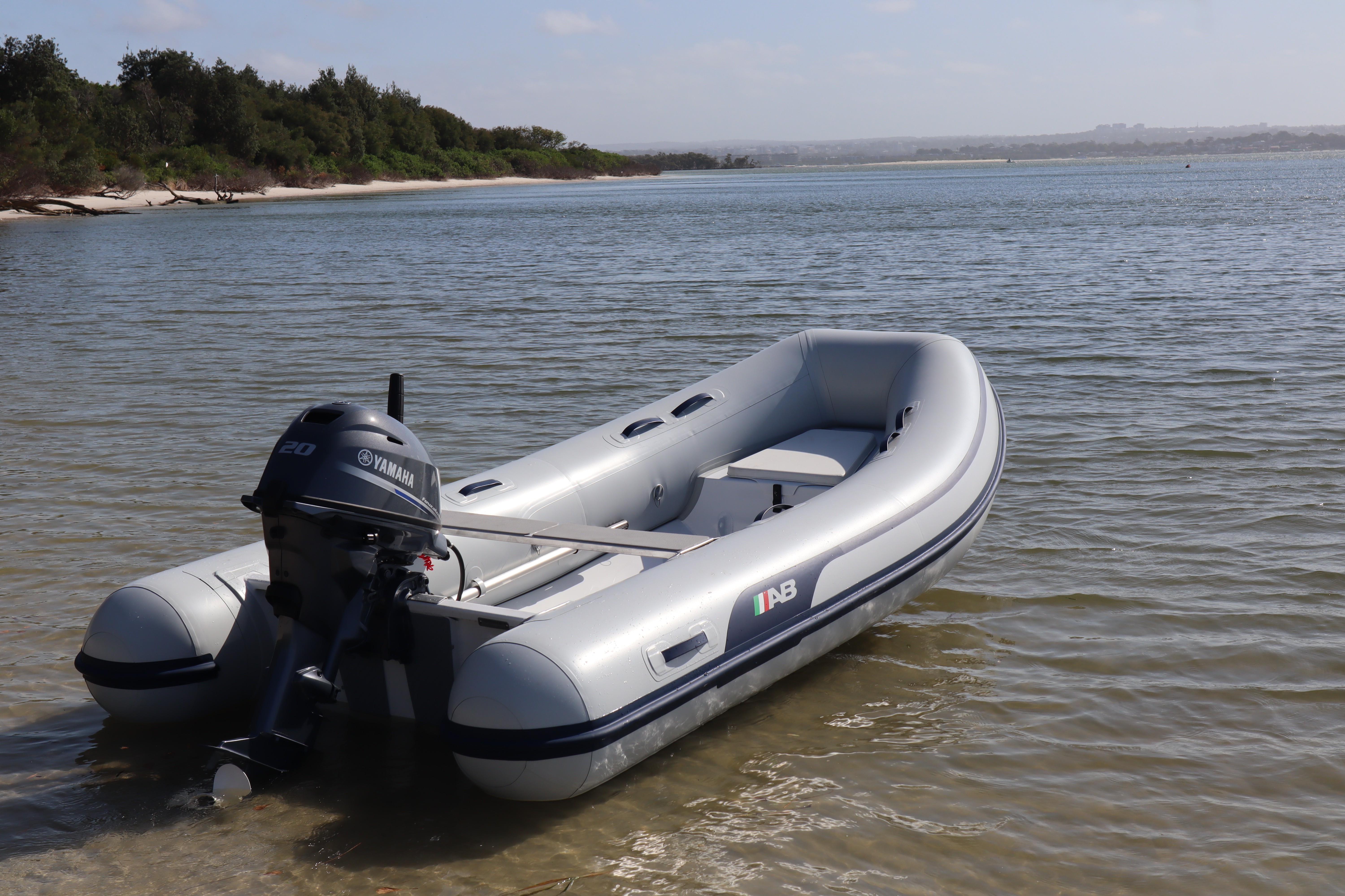 A winding road cuts through rocky terrain, surrounded by patches of green grass and illuminated by sunlight.