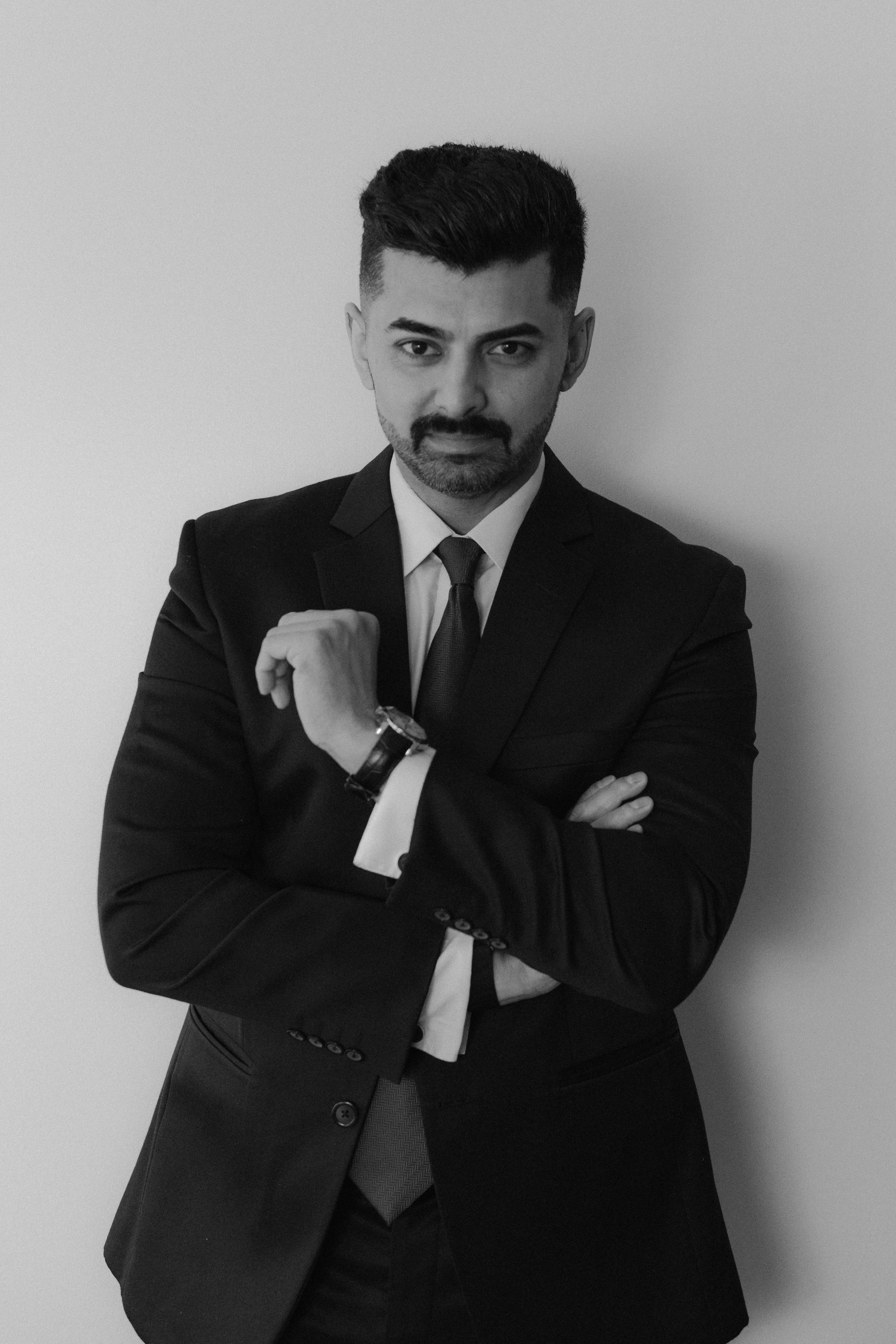 Mature man with glasses and a trimmed beard smiling confidently, standing in warm natural light against a modern backdrop.