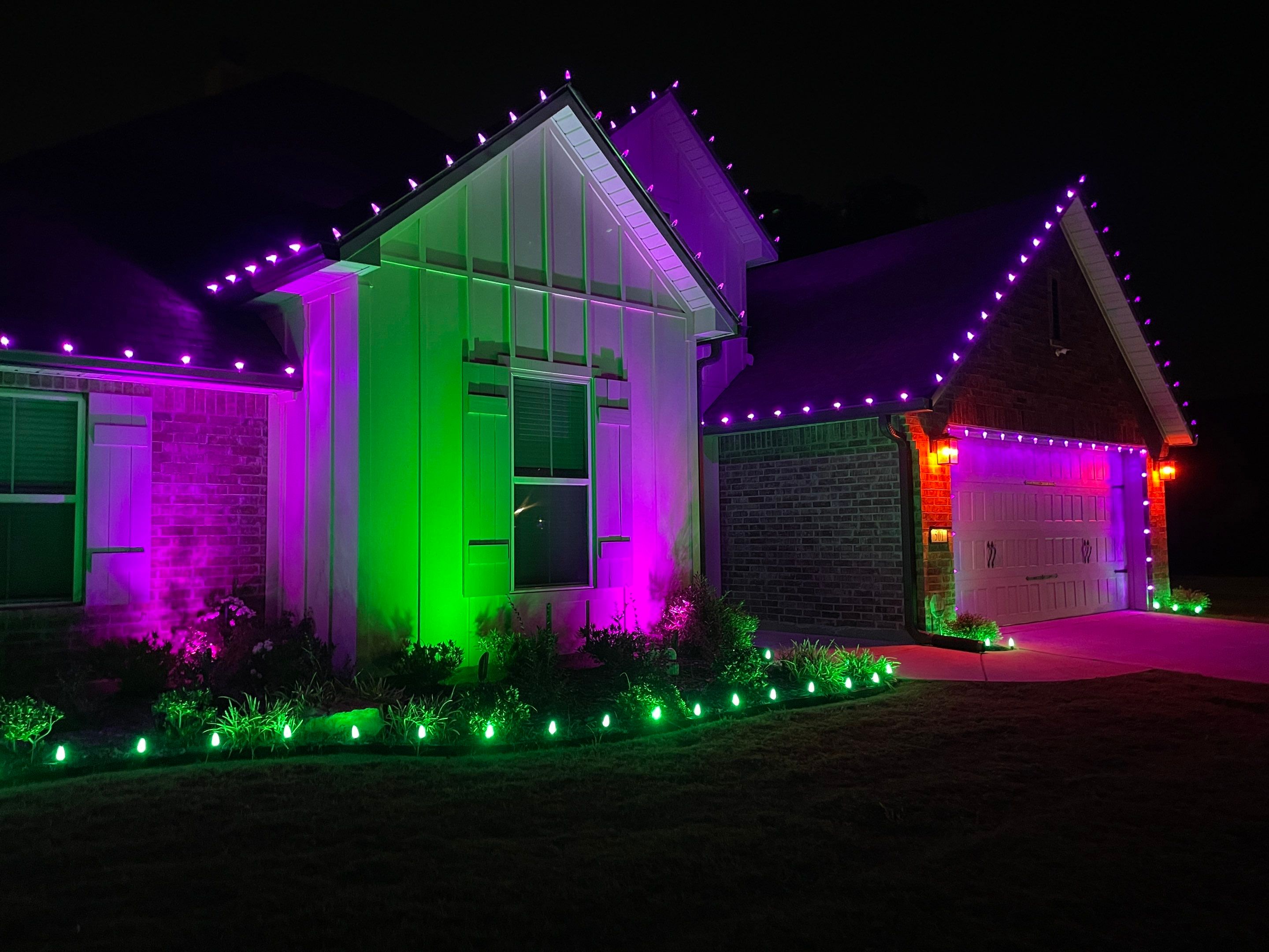 Professional holiday lighting in Shreveport featuring multicolor roofline lights and window display on a brick home.