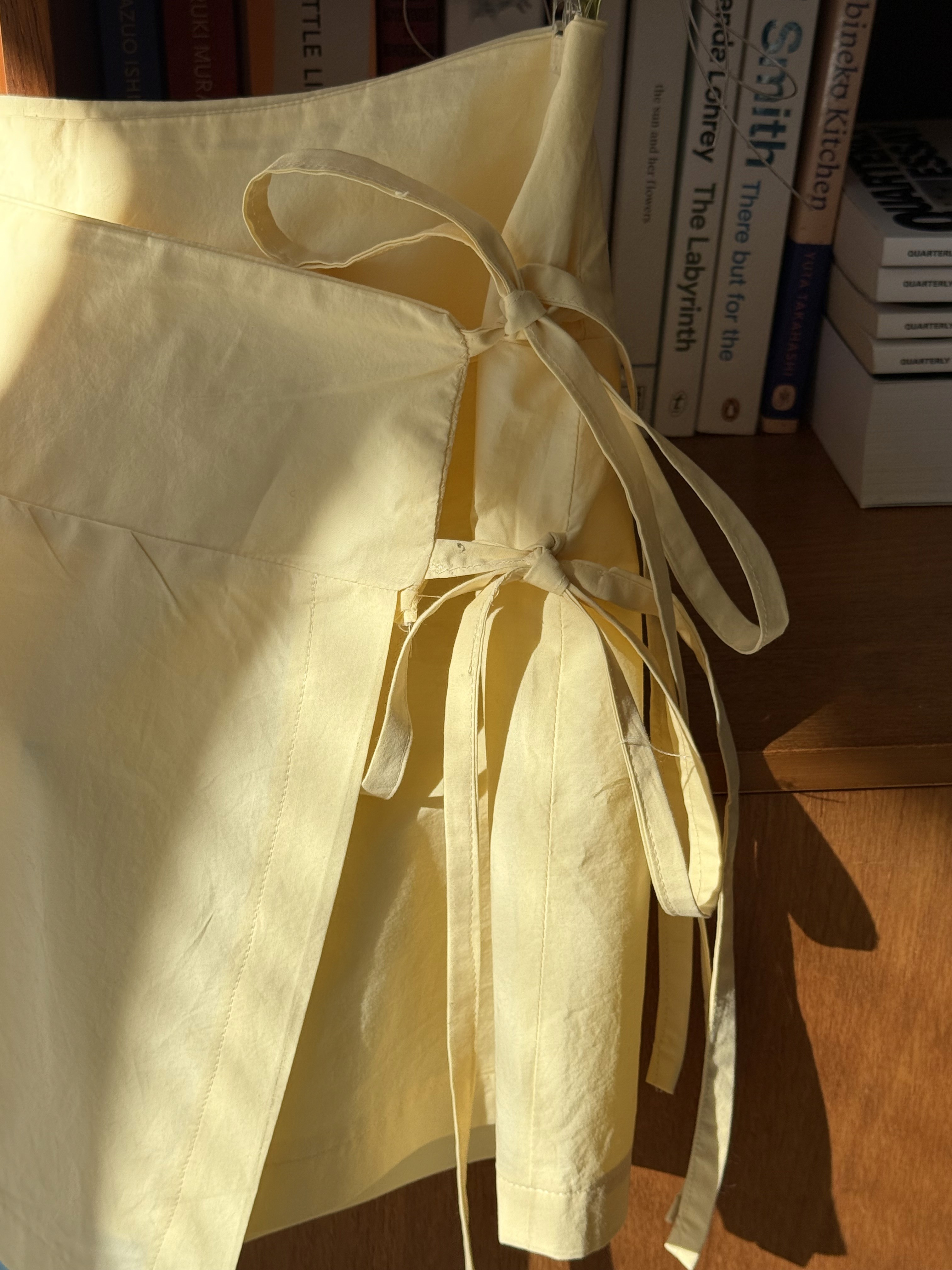 closeup of the ties of a short yellow wrap skirt