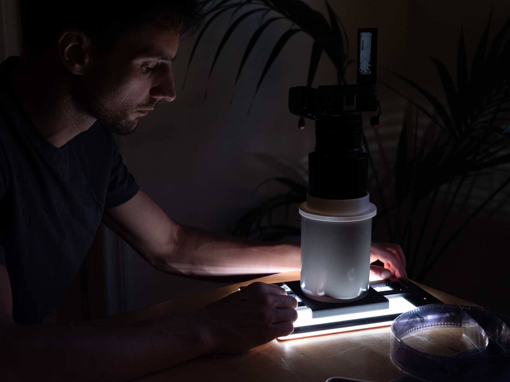 Photographer scanning film with a custom camera setup DSLR on a light box