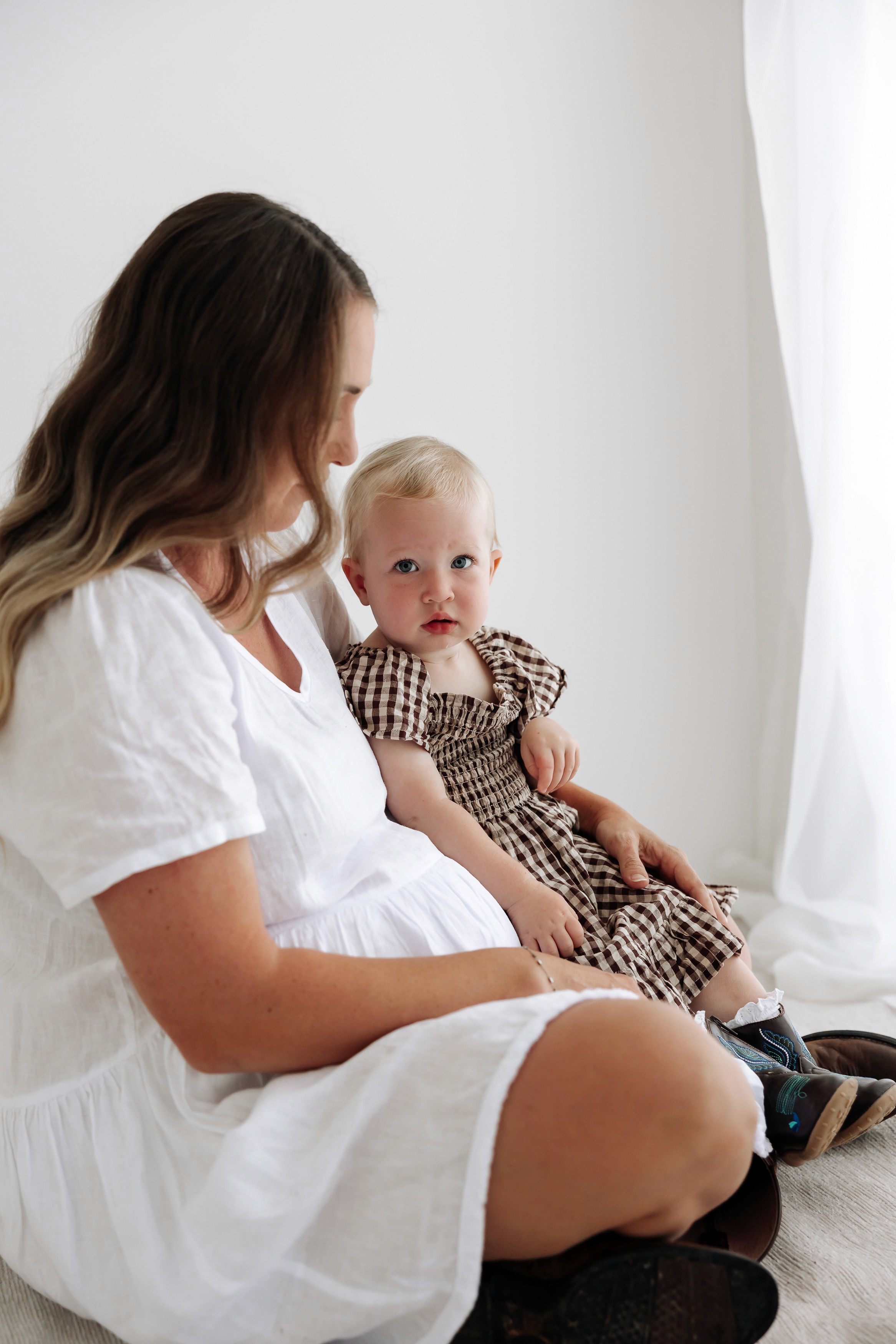 Motherhood portrait of a pregnant woman and her daughter together in a minimalist photography studio