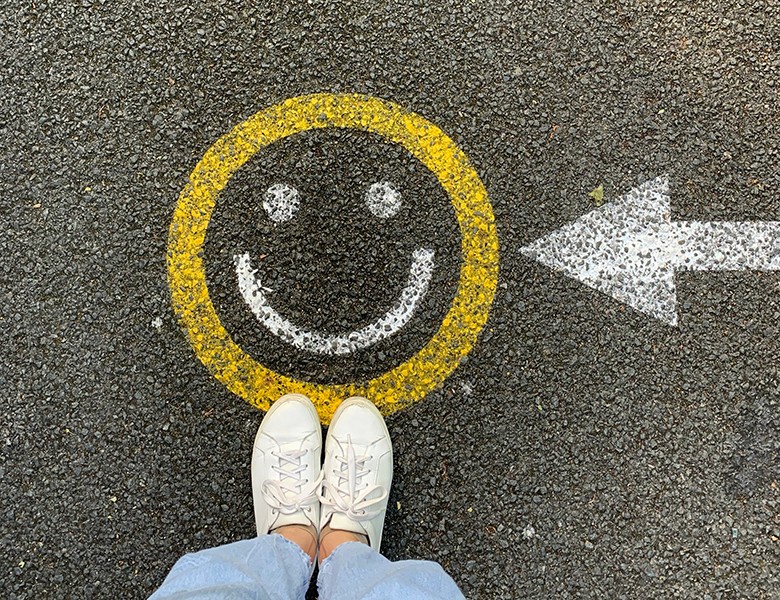 Yellow smiley face and arrow painted on pavement, symbolizing creativity, clarity, and positive brand direction.