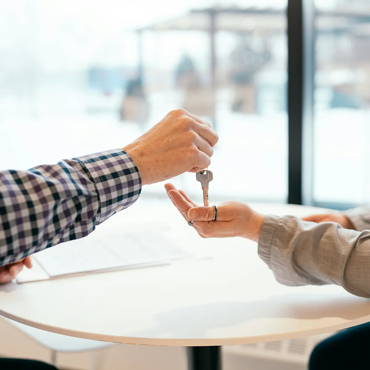 Close-up of one person handing house keys to another, symbolising handover or ownership.