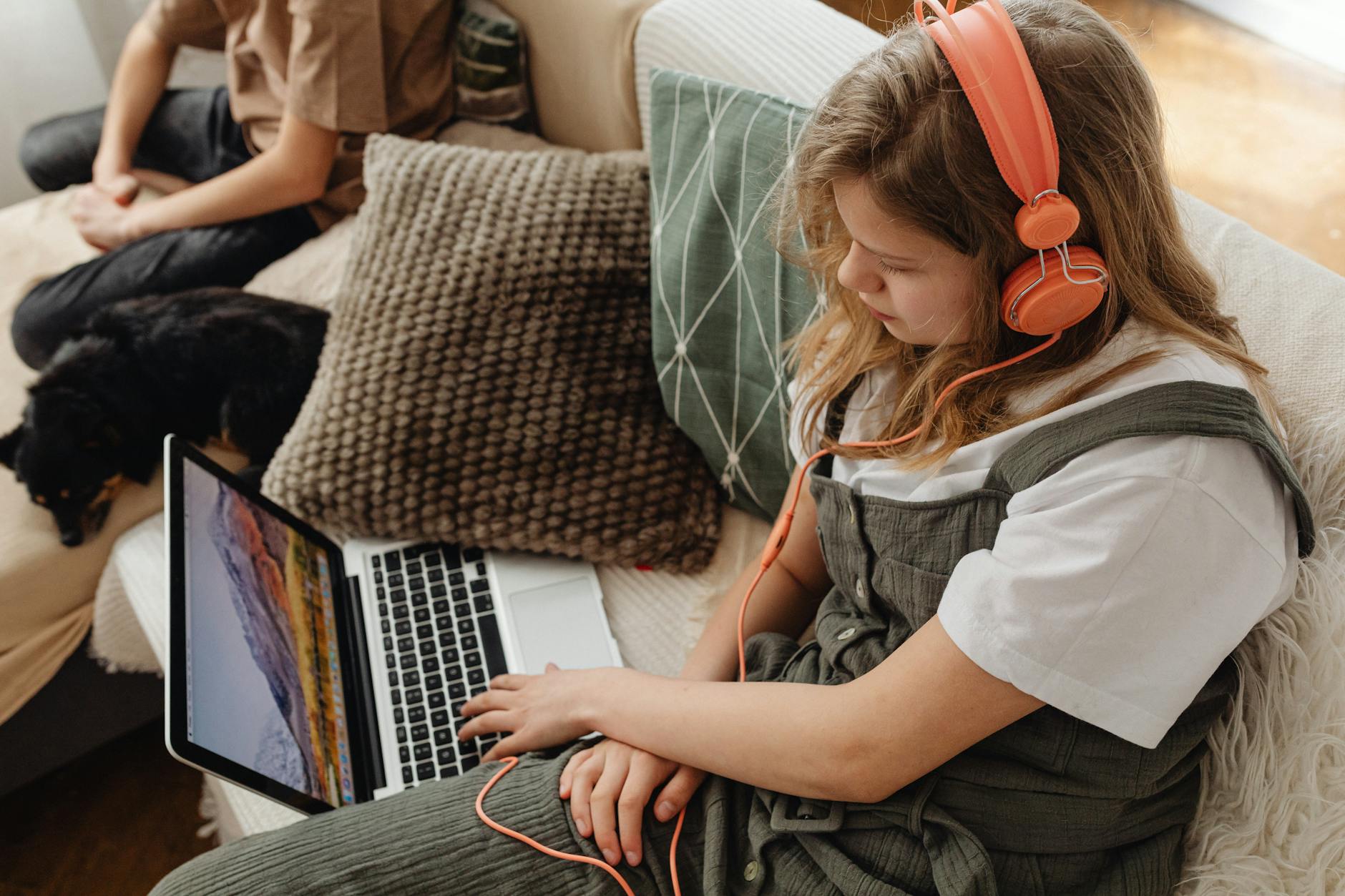 A young girl wearing headphones looks at a laptop screen during a virtual lesson at the best brain learning center.