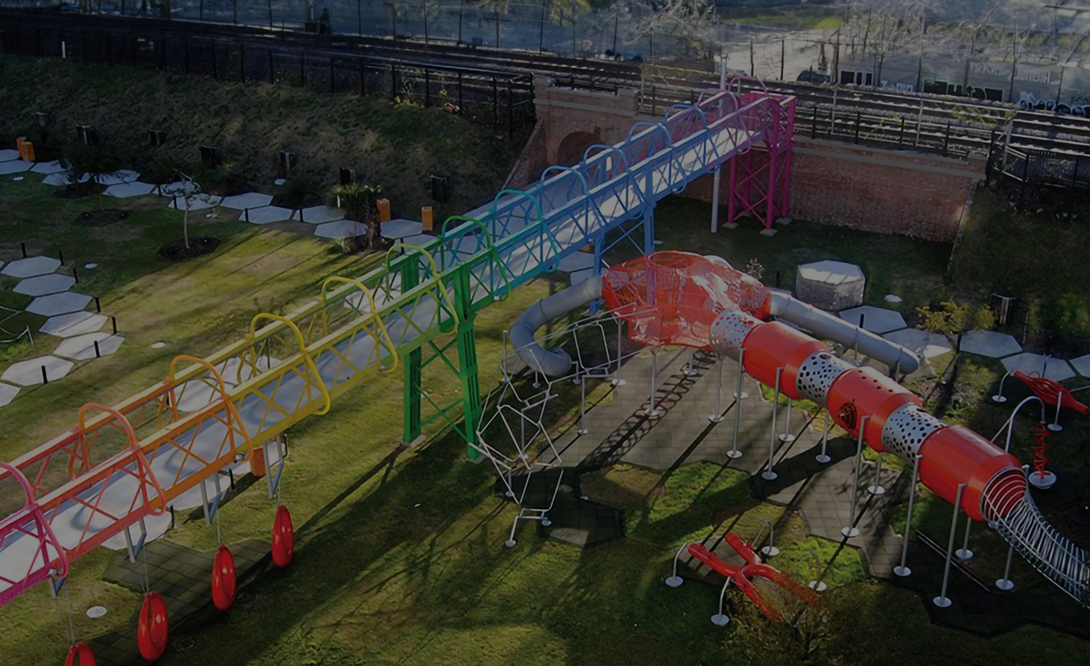 A vibrant playground with a multicolored tunnel slide and climbing structures on a green lawn. Playful and inviting atmosphere under a sunny sky.