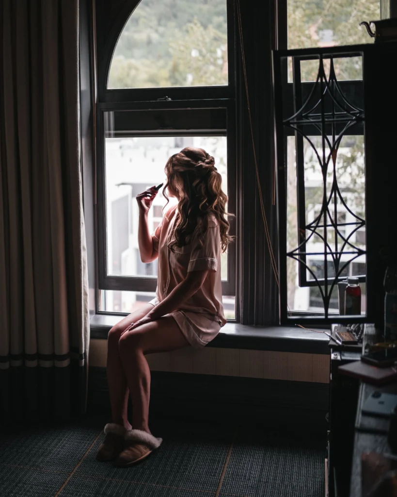 Bride getting ready by window light at Aspen Meadows Resort Wedding in Aspen