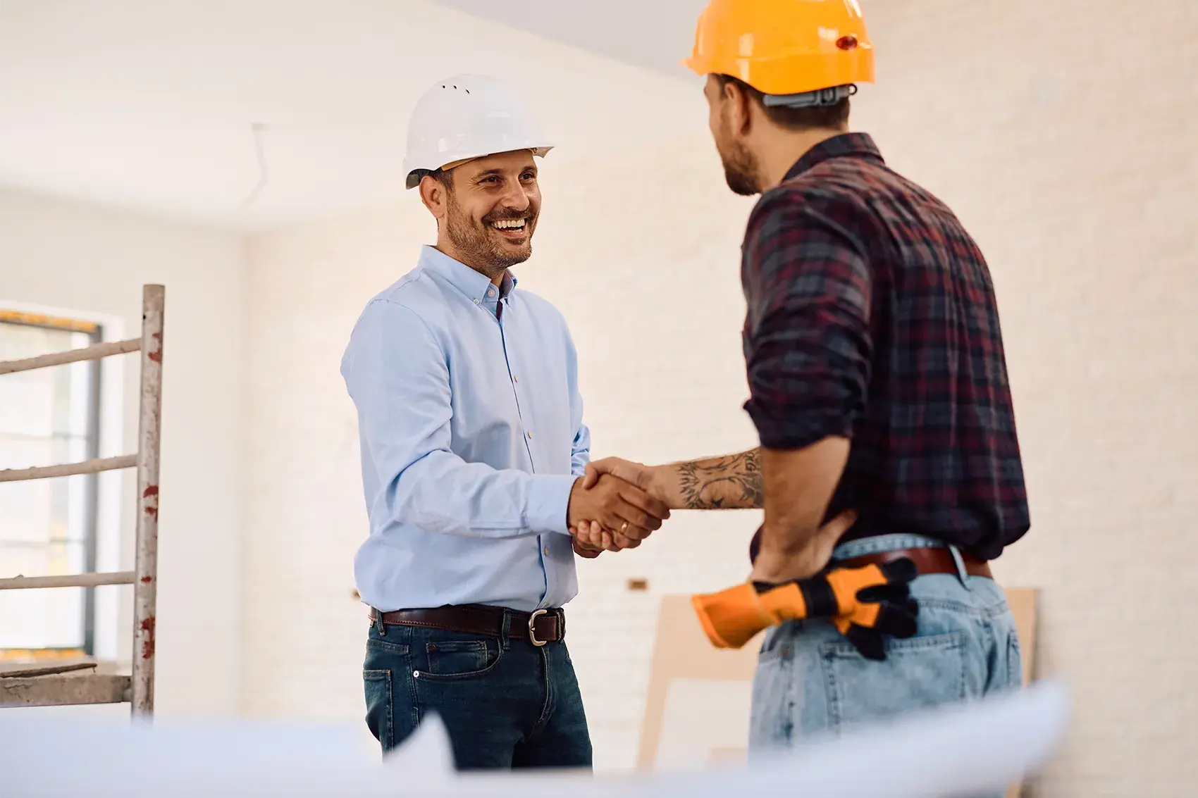 Zwei Bauleiter geben sich lächelnd die Hand