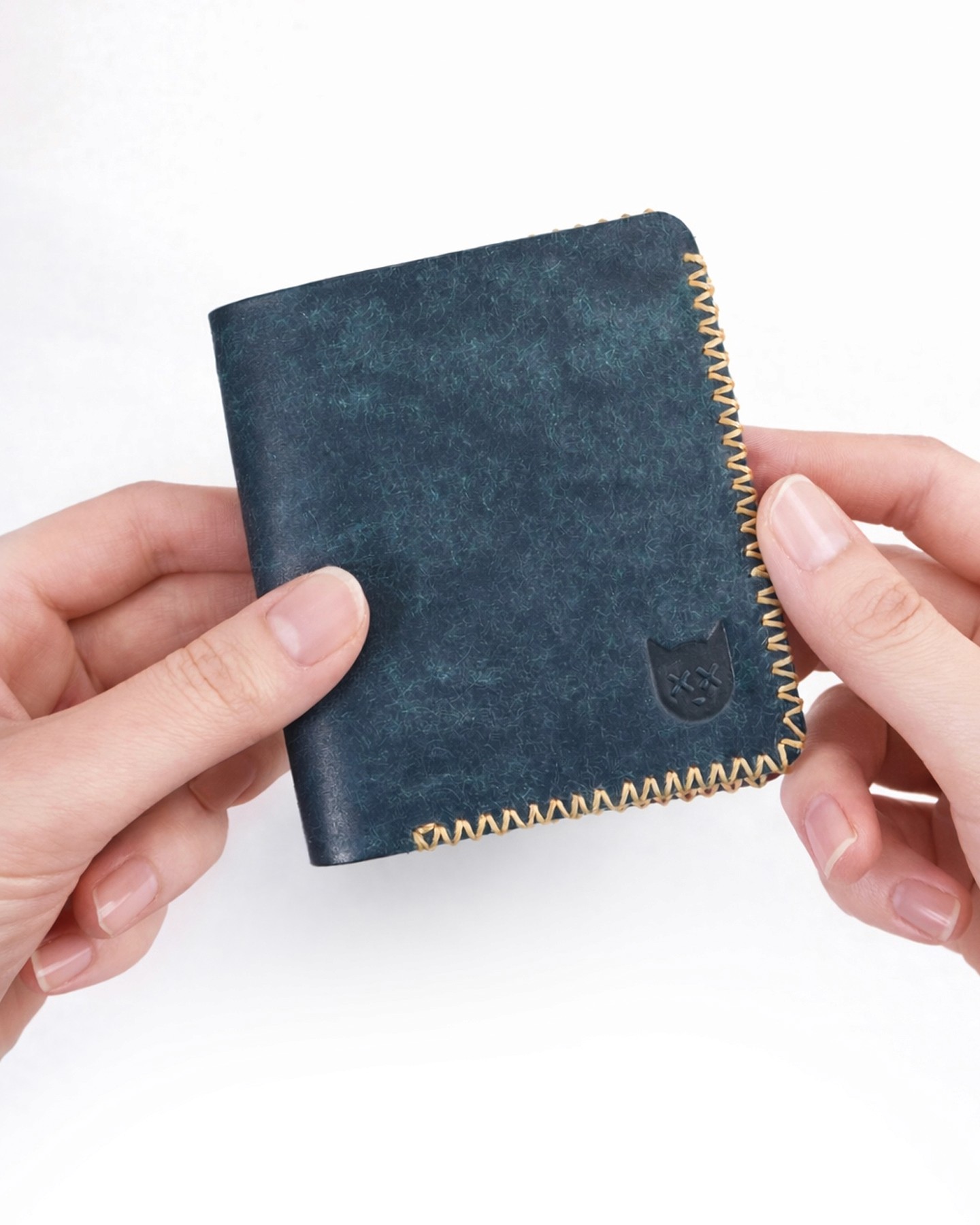 Crosstitch Leather handmade tan wallet with yellow cross-stitch edge and embossed cat emblem.