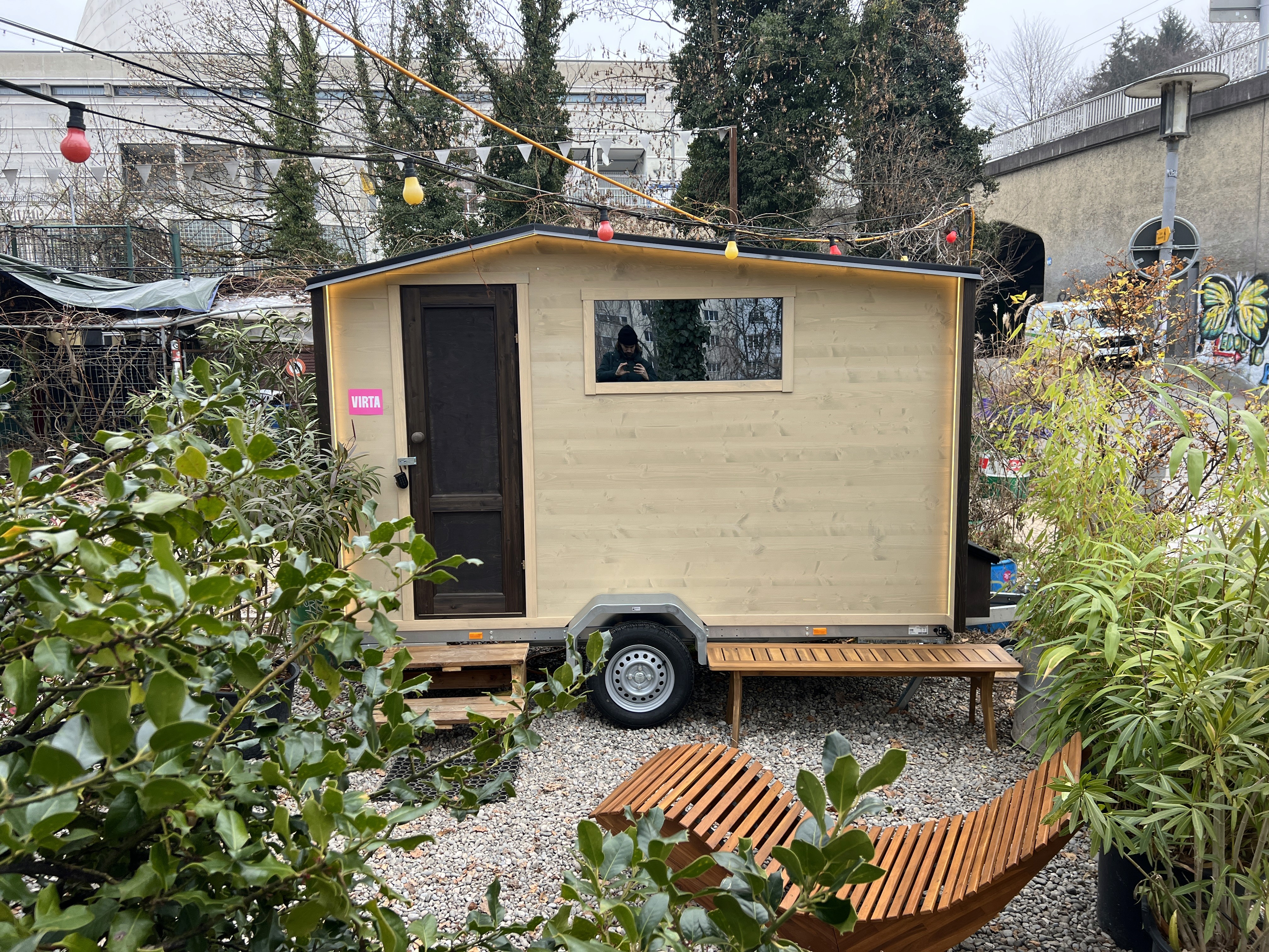 LÖYLY-Sauna bei der Stazione Paradiso in Zürich, eingebettet in einen urbanen Garten mit bunter Lichterdeko.