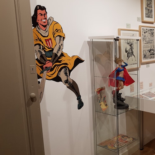 博物馆展览包括一幅中世纪战士的墙面壁画,一个陈列着超级英雄人物的玻璃橱窗,以及各种与漫画相关的物品。