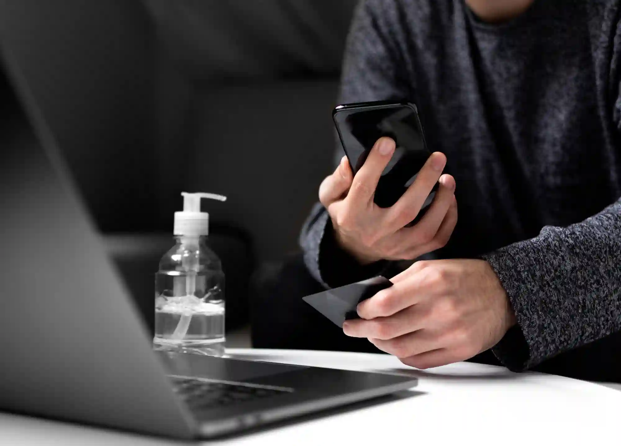 A person using a smartphone and laptop to manage digital tasks, illustrating modern workspace connectivity and technology integration.
