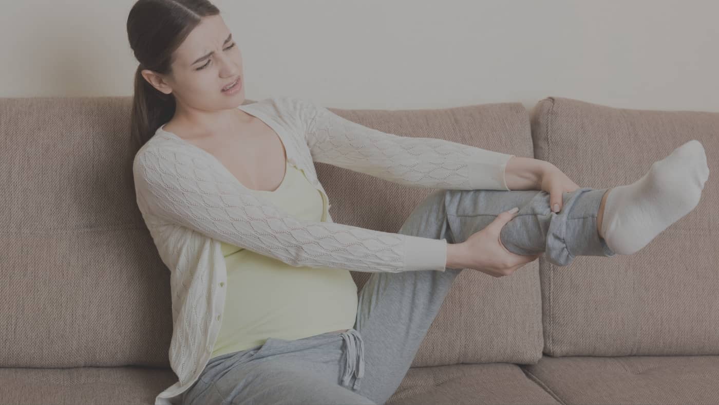 Femme enceinte touchant ses chevilles gonflées pour illustrer la rétention d'eau pendant la grossesse.