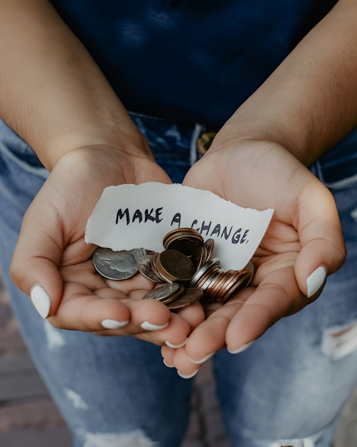 Open hands holding coins and a note that reads make a change