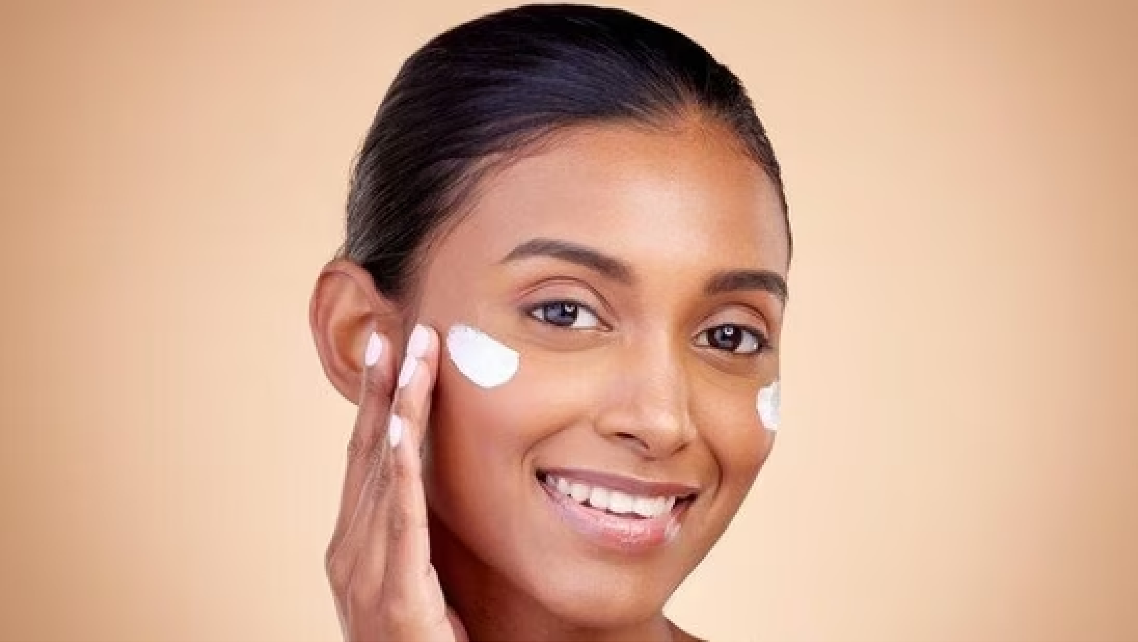 Smiling Indian woman applying face cream for healthy skin