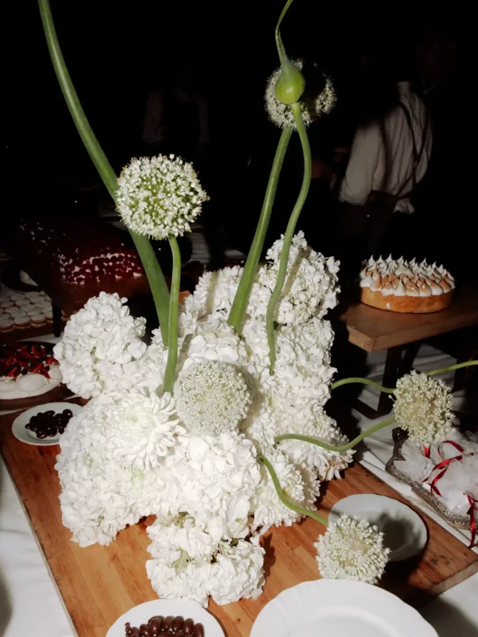 Centro de mesa con flores blancas sobre tabla de madera para eventos que buscan elegancia natural con texturas orgánicas y contraste visual.