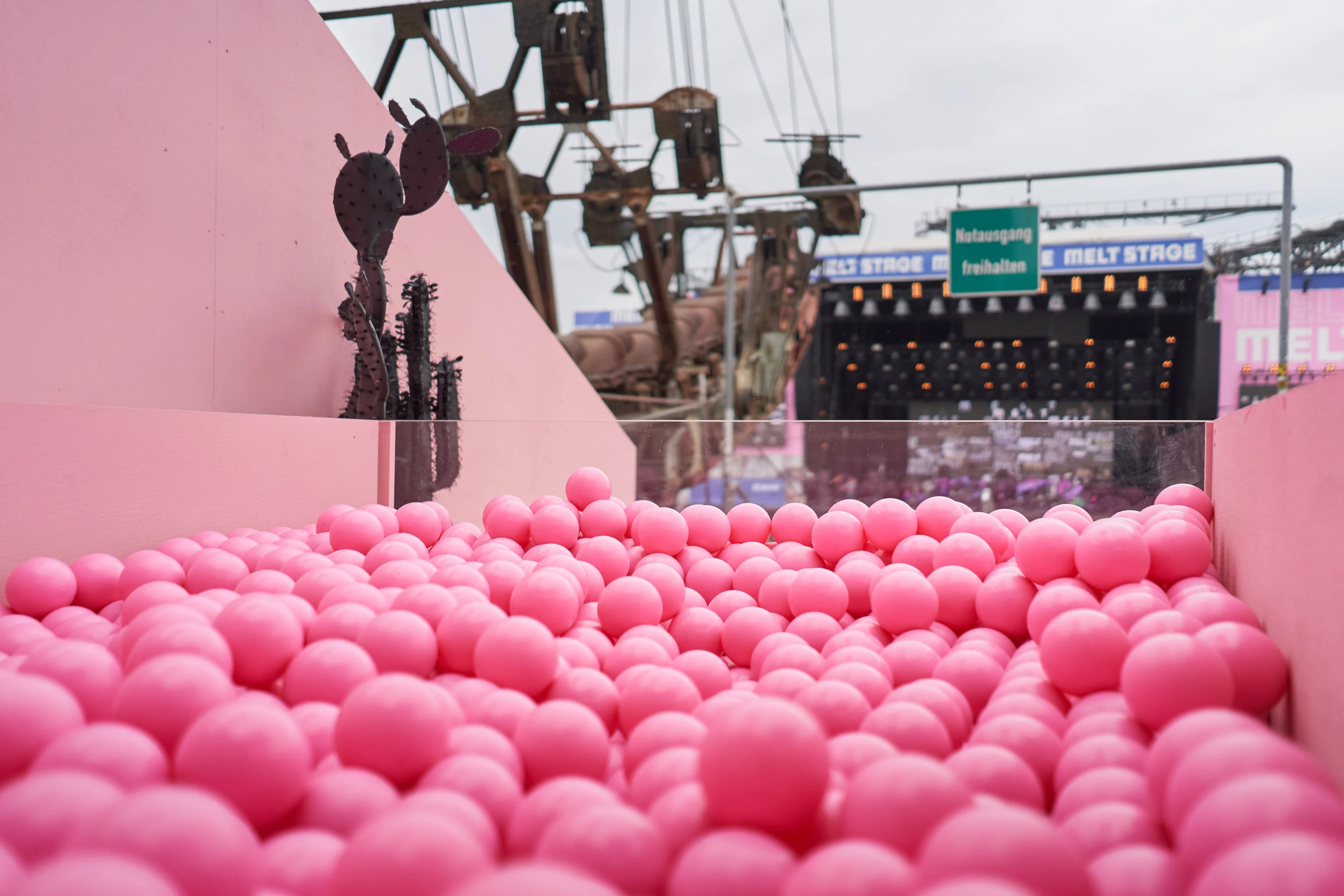 Pink ball pit on the Klarna deck overlooking the Melt Festival main stage and industrial machinery.