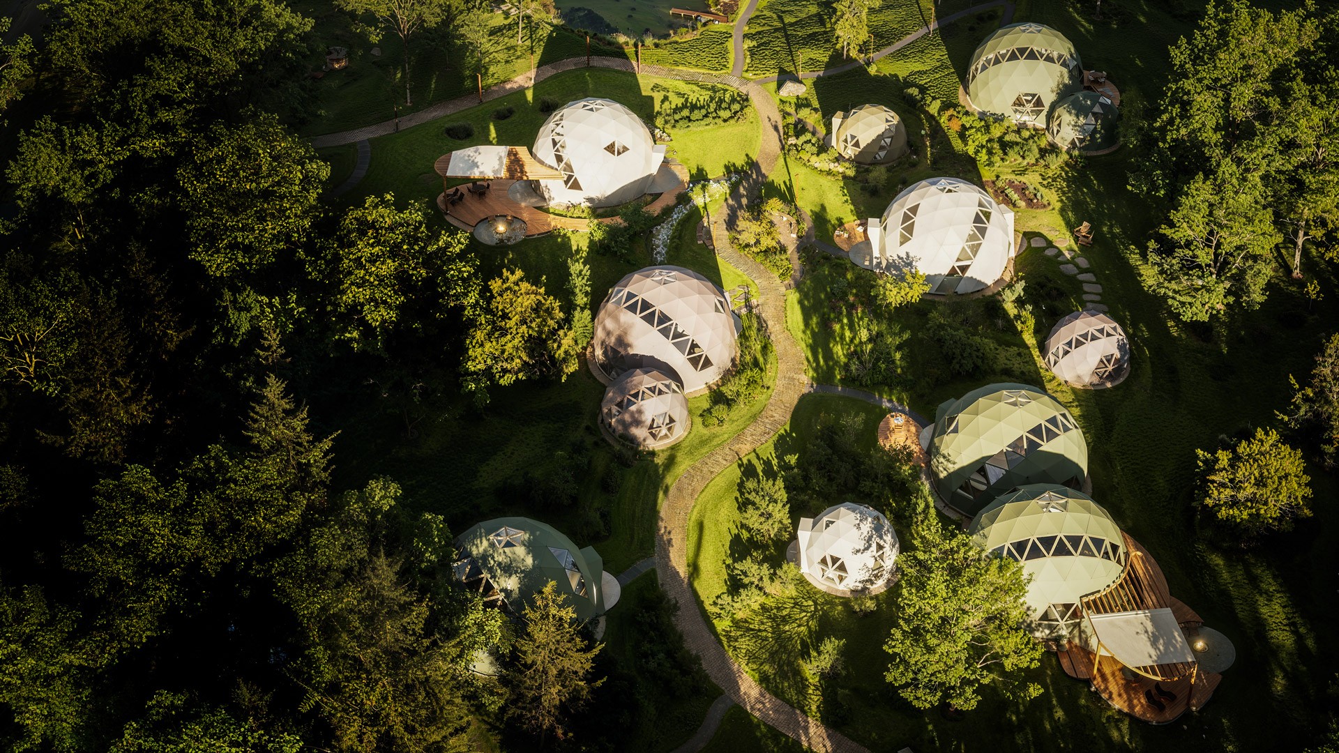 A serene landscape features two dome-shaped structures amidst lush greenery.