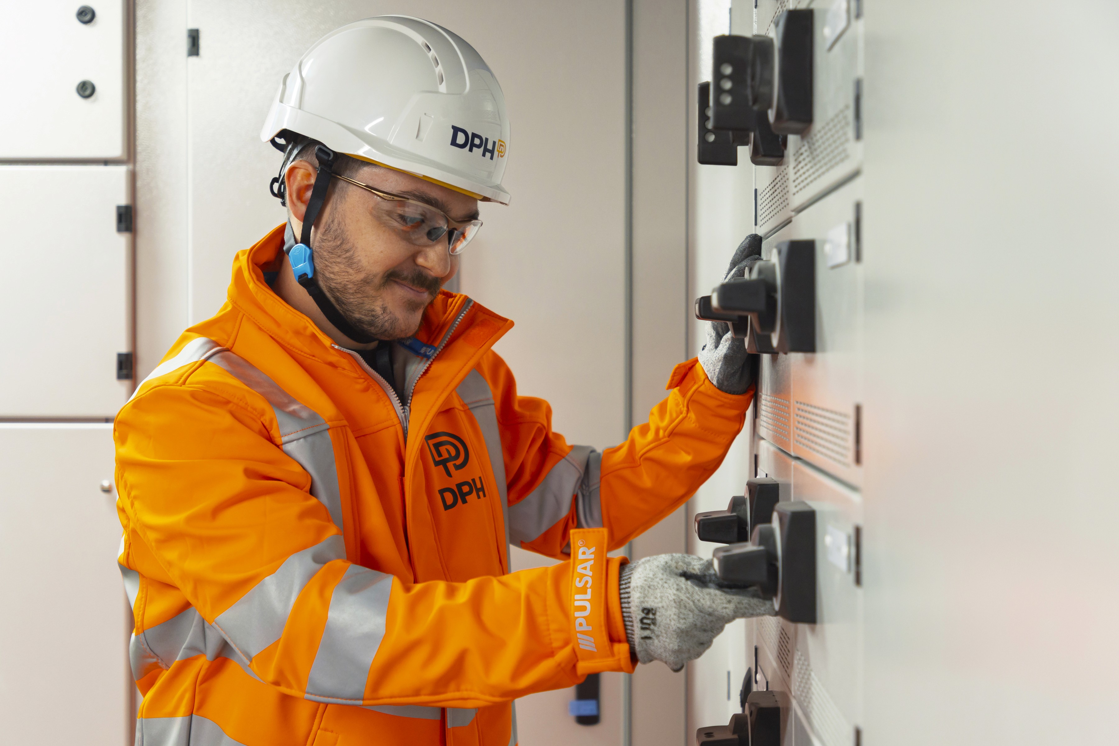 Modern glass building with illuminated facade and trees at sunset