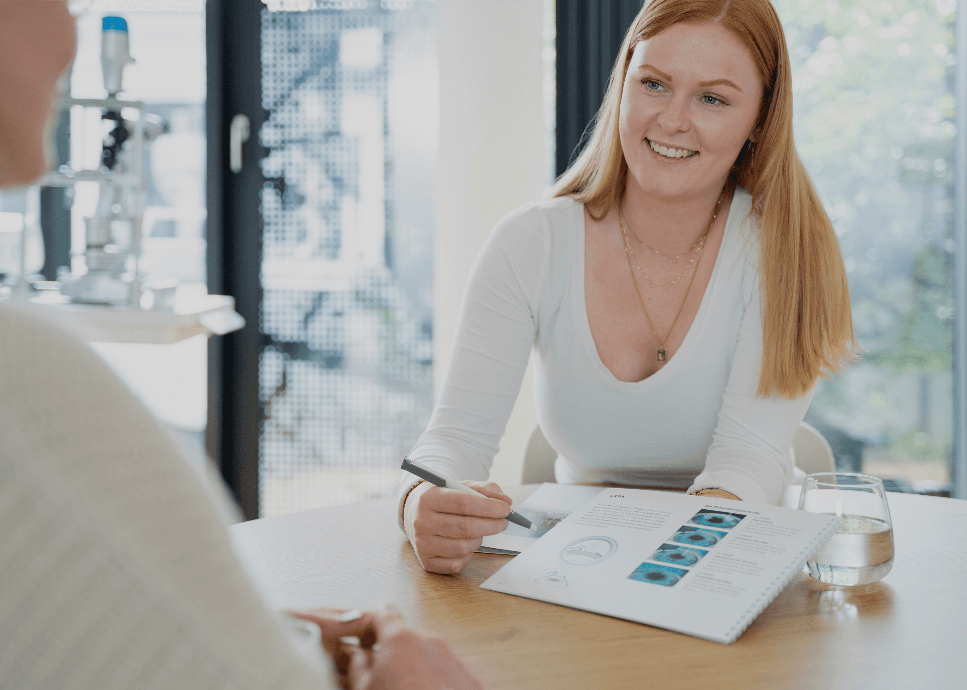 Beraterin mit Brille lächelt während eines Beratungsgesprächs in einer Augenlaserklinik