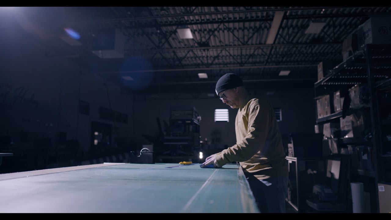 Man at a workbench in a warehouse workshop measuring fabric.